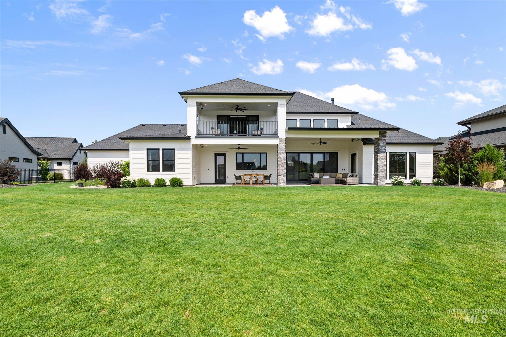 Back of property with ceiling fan, an outdoor hangout area, a lawn, and a patio