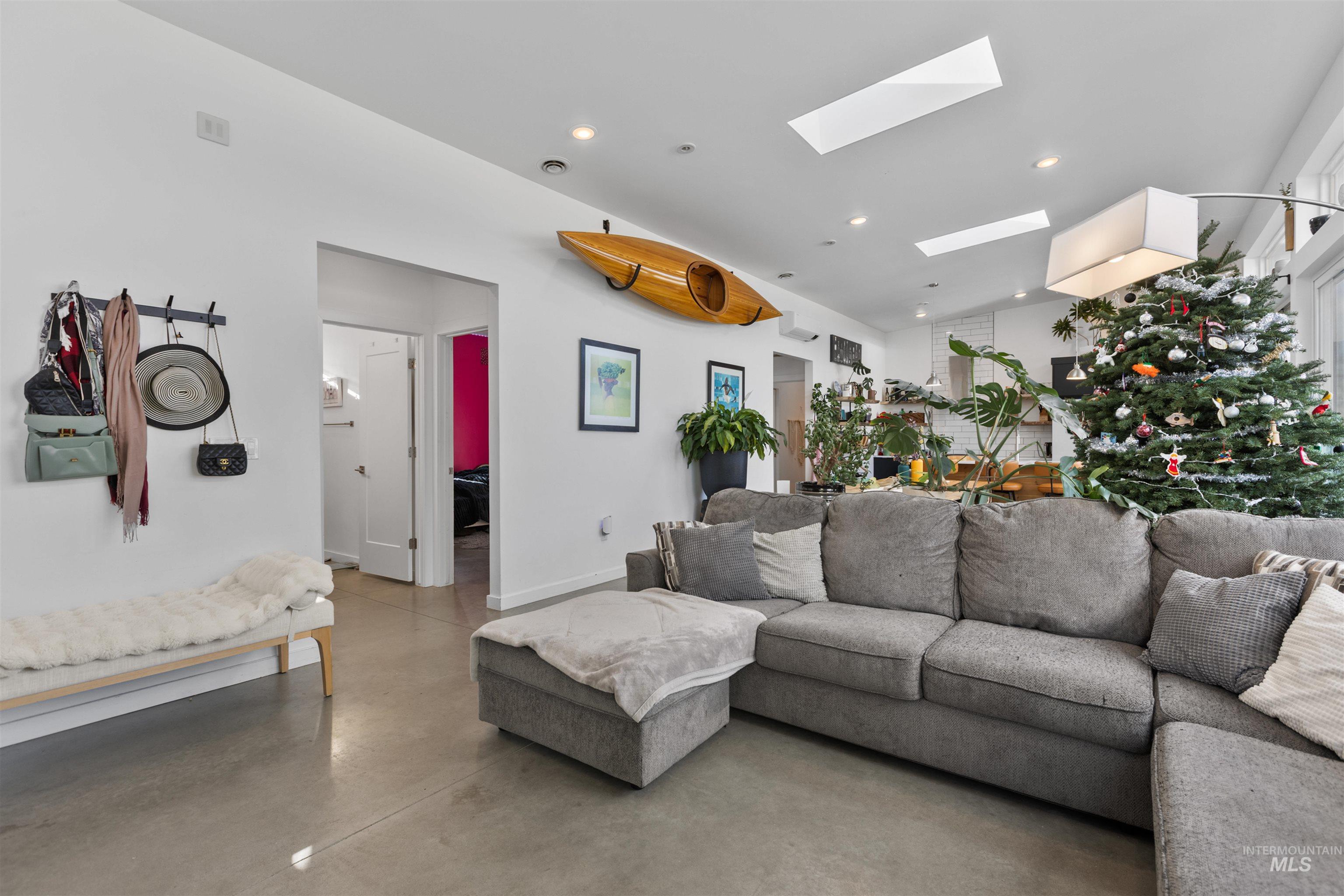 Living area with a skylight, finished concrete floors, and recessed lighting