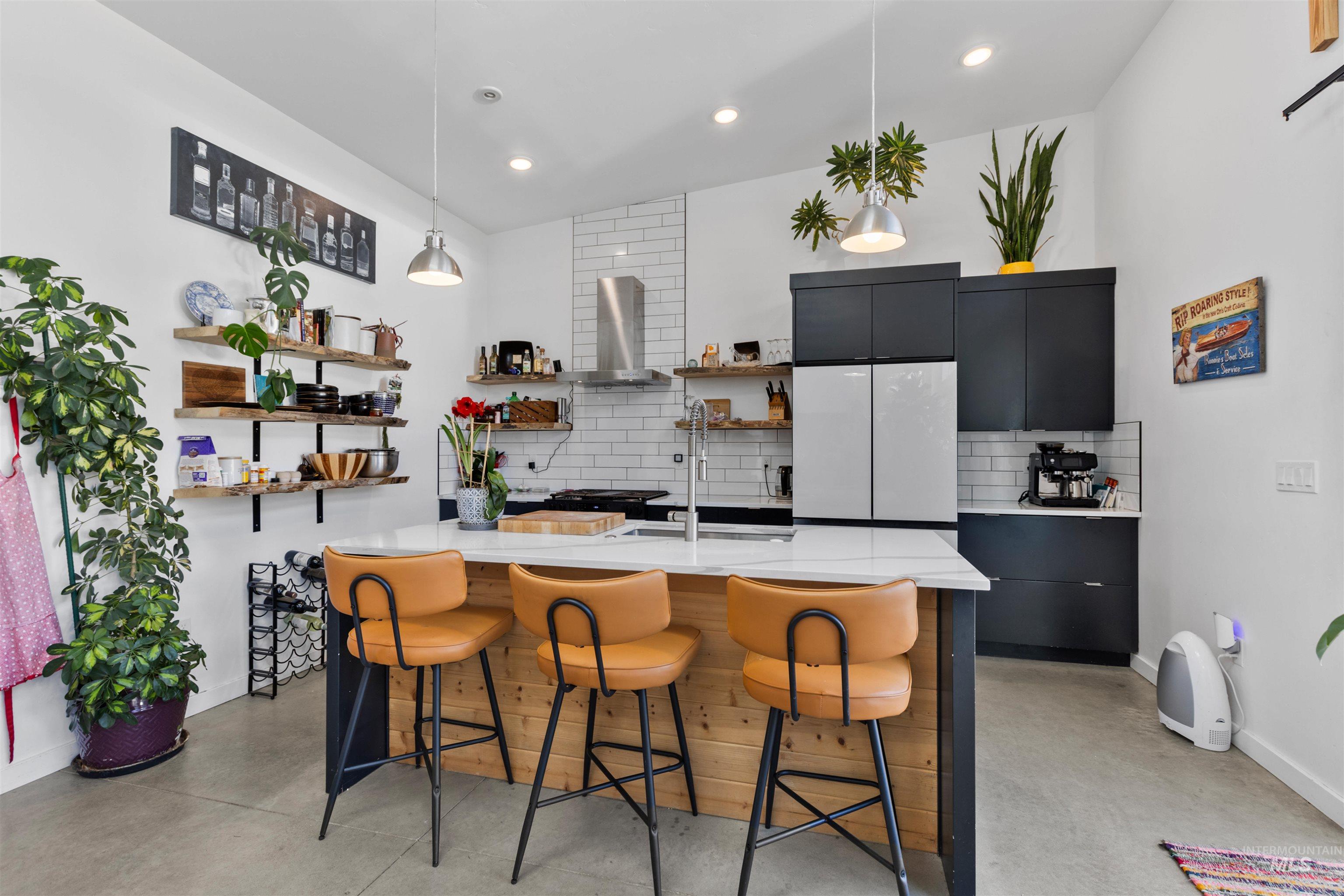Kitchen with a breakfast bar, dark cabinets, open shelves, concrete flooring, and recessed lighting