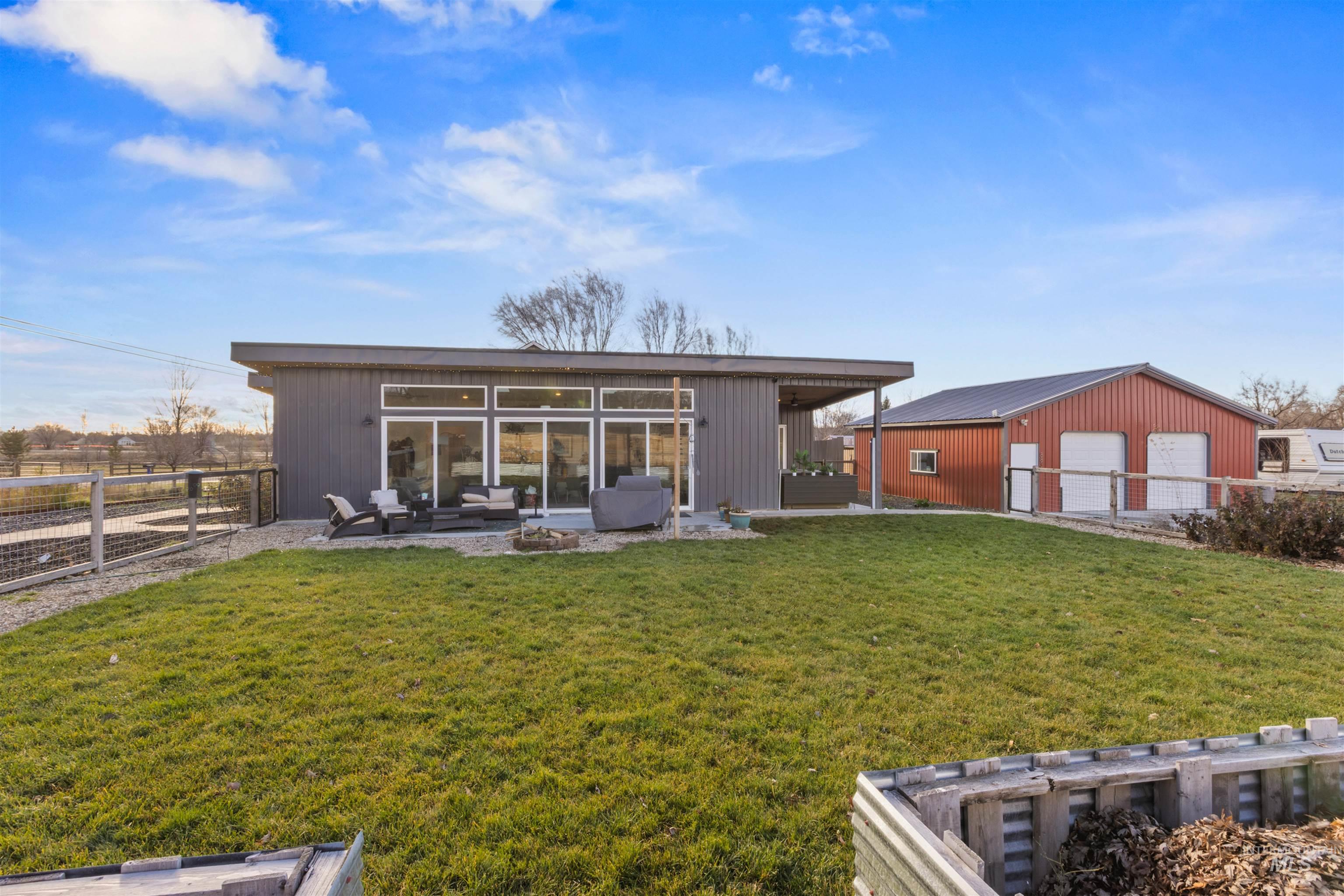 Rear view of property with a patio, an outbuilding, an outdoor living space with a fire pit, and a detached garage