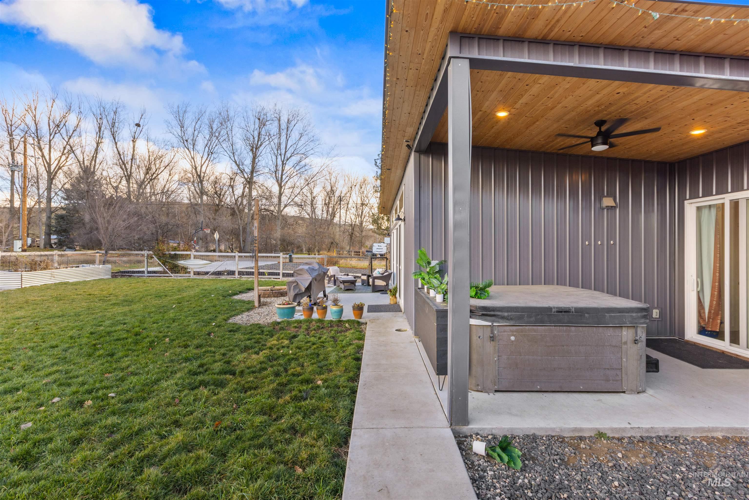 View of green lawn featuring a hot tub, a patio, and ceiling fan