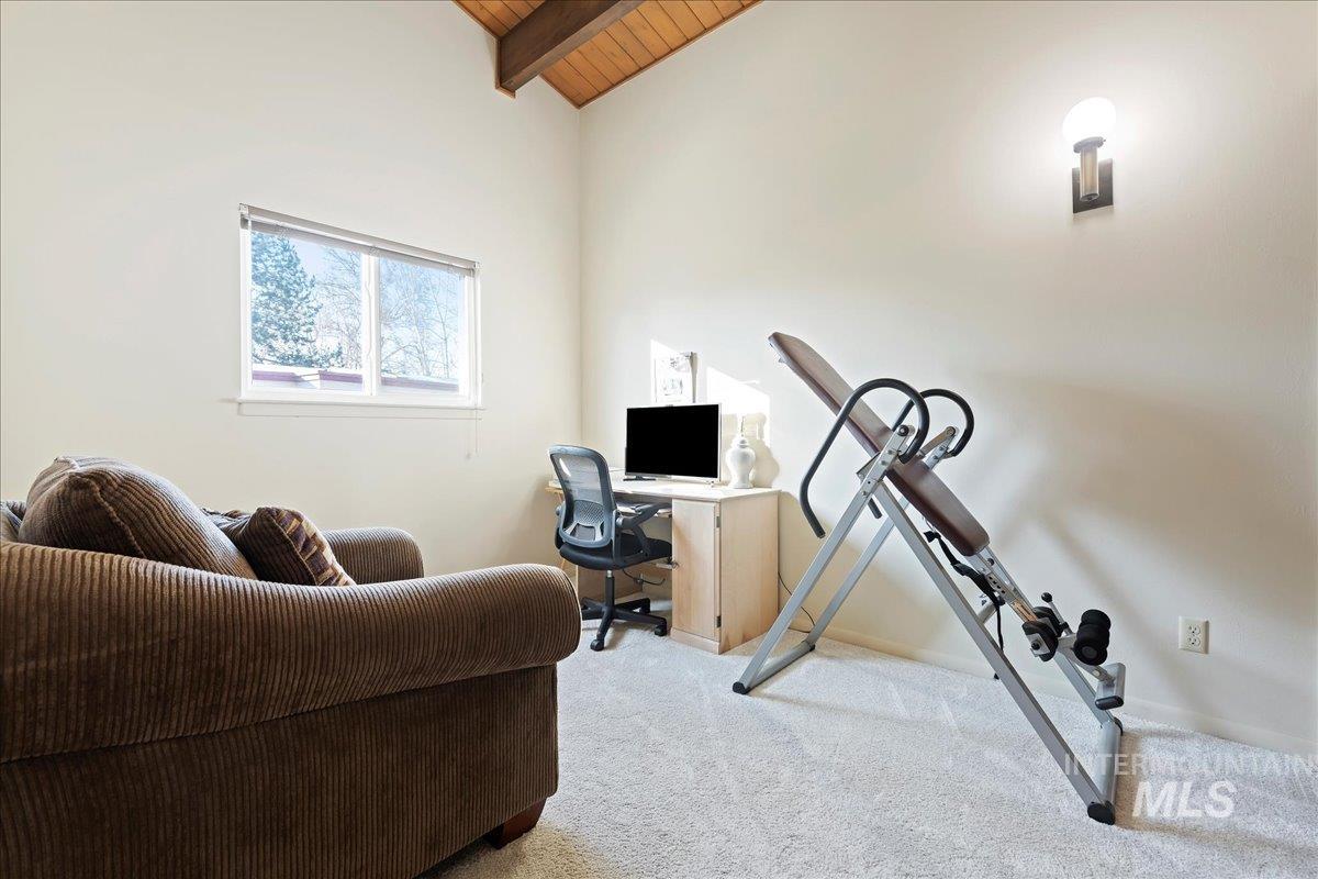 Carpeted office space with wood ceiling and baseboards