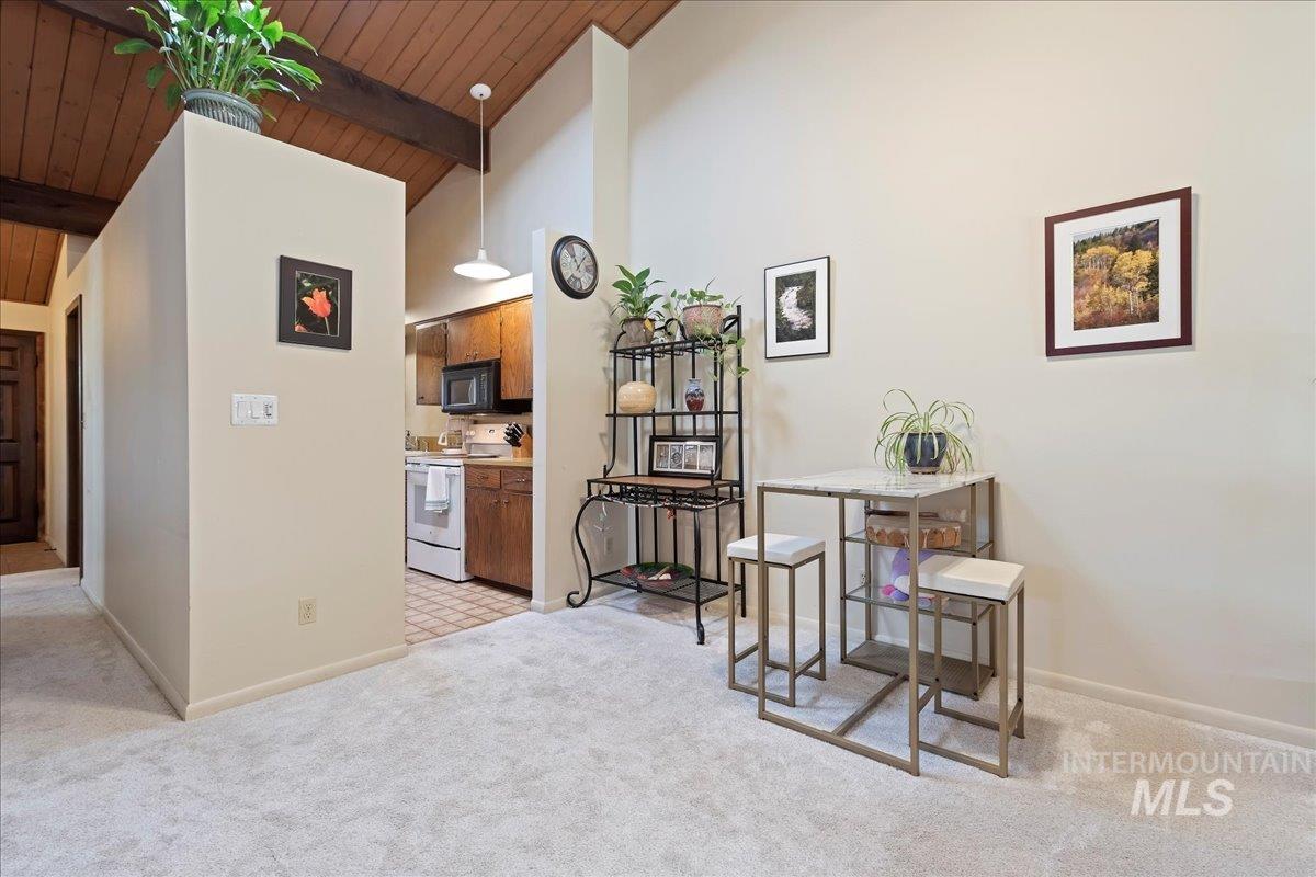 Sitting room with light carpet, high vaulted ceiling, and a wood ceiling with exposed beams