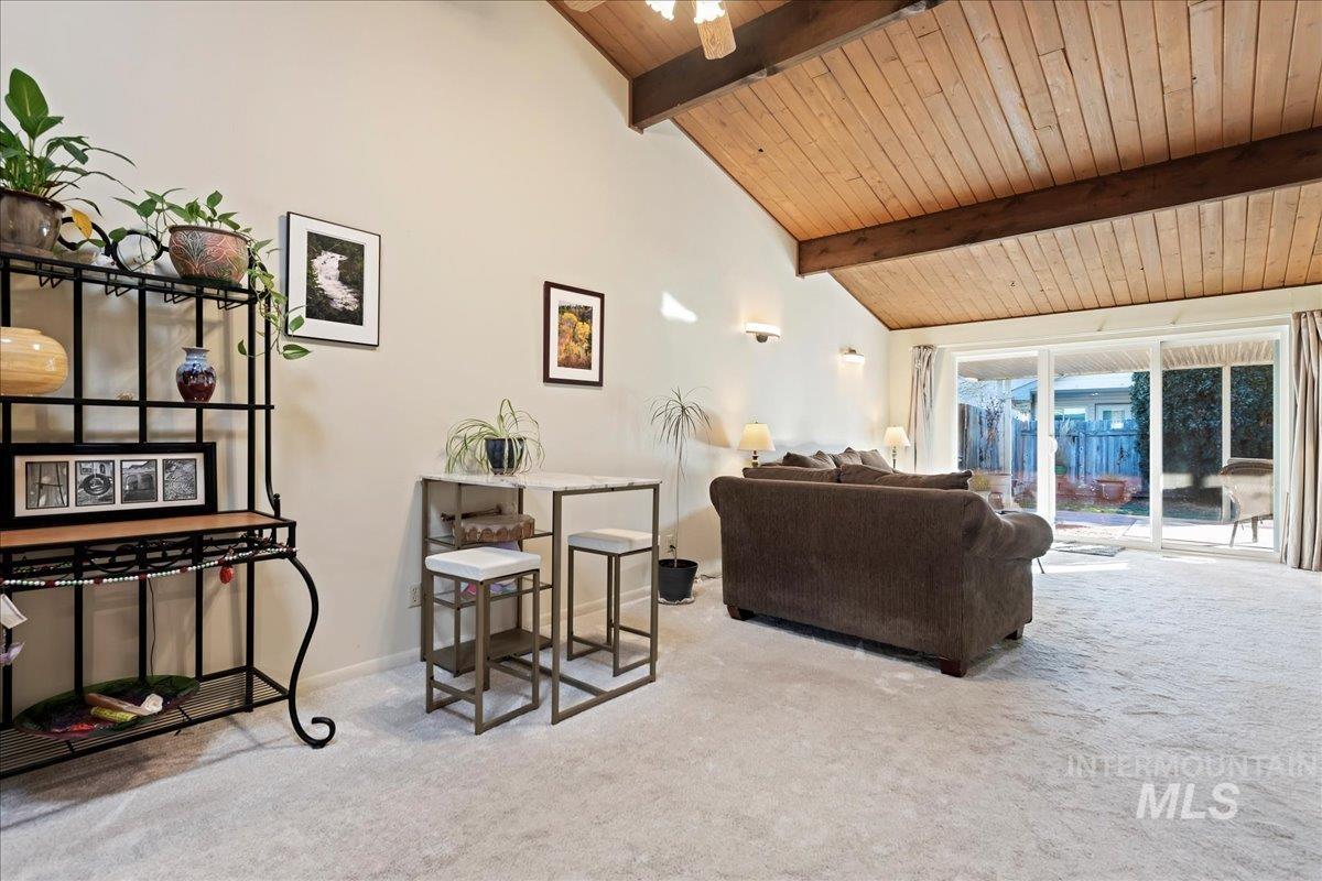 Living room featuring carpet flooring, a wooden ceiling with exposed beams, high vaulted ceiling, and a ceiling fan