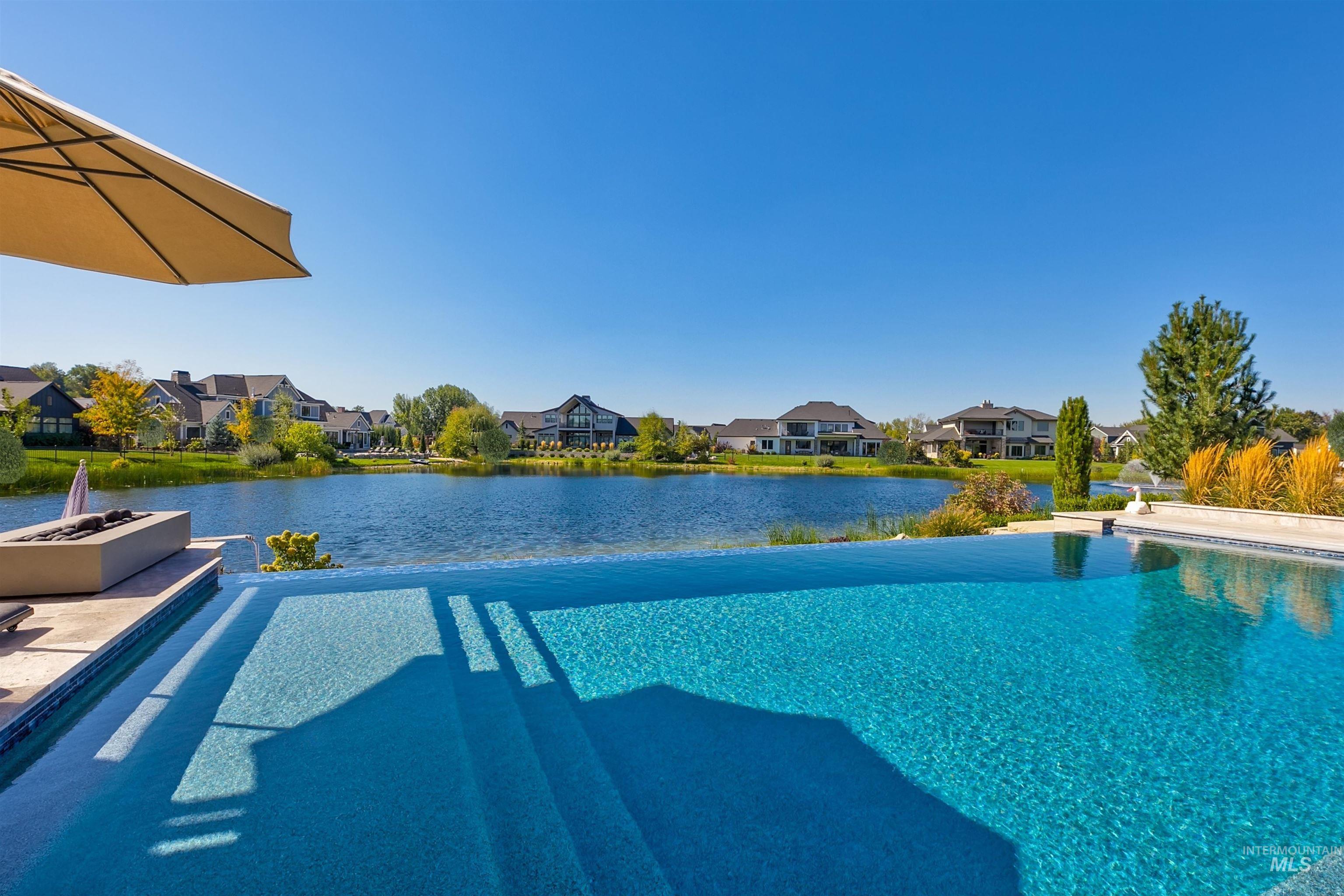 Outdoor pool with a water view, a residential view, and an outdoor fire pit