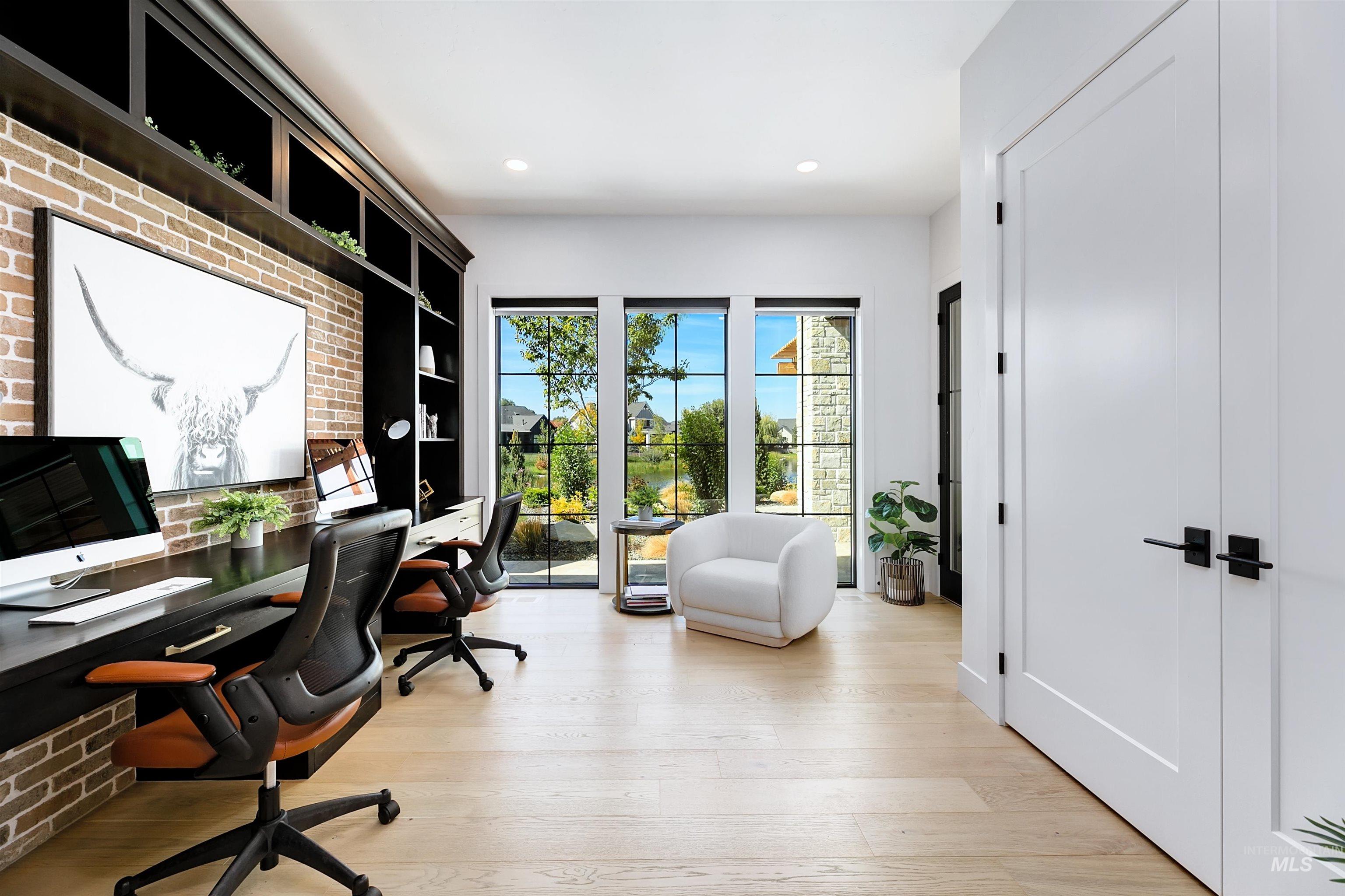 Home office featuring light wood-style floors, recessed lighting, and brick wall