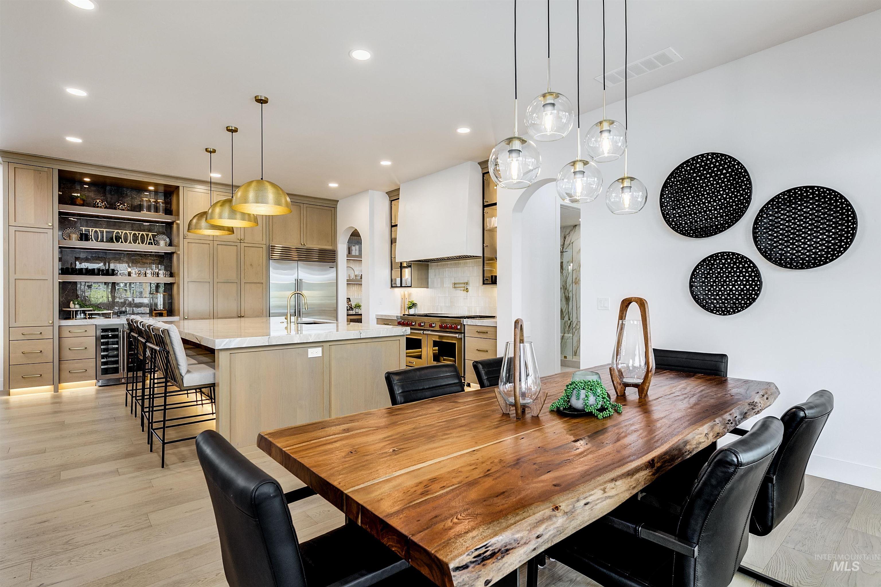 Dining area with light wood finished floors, beverage cooler, and recessed lighting