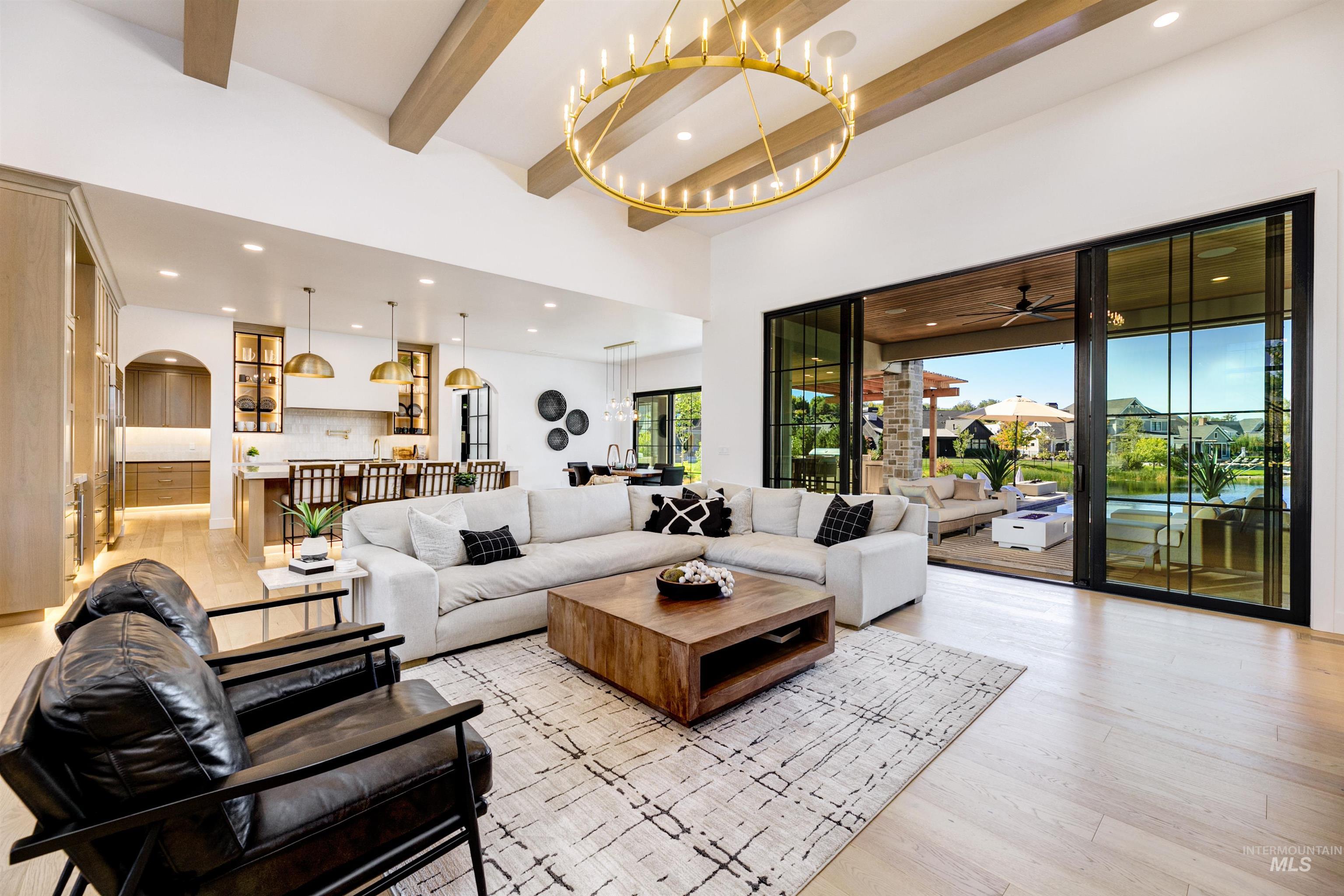 Living room with beam ceiling, recessed lighting, light wood-style flooring, a chandelier, and arched walkways
