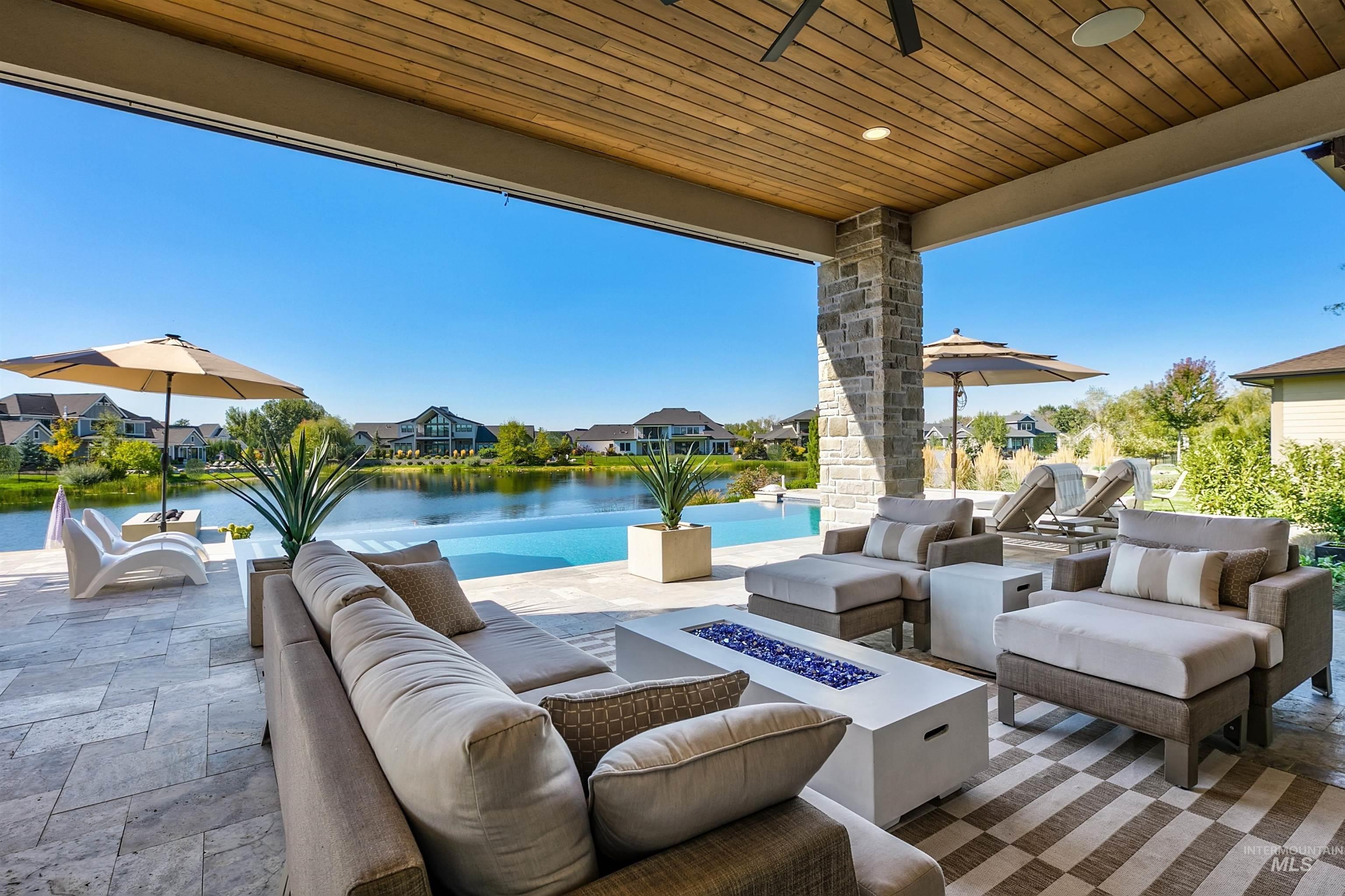 View of patio featuring an outdoor living space with a fire pit, a residential view, a water view, and ceiling fan