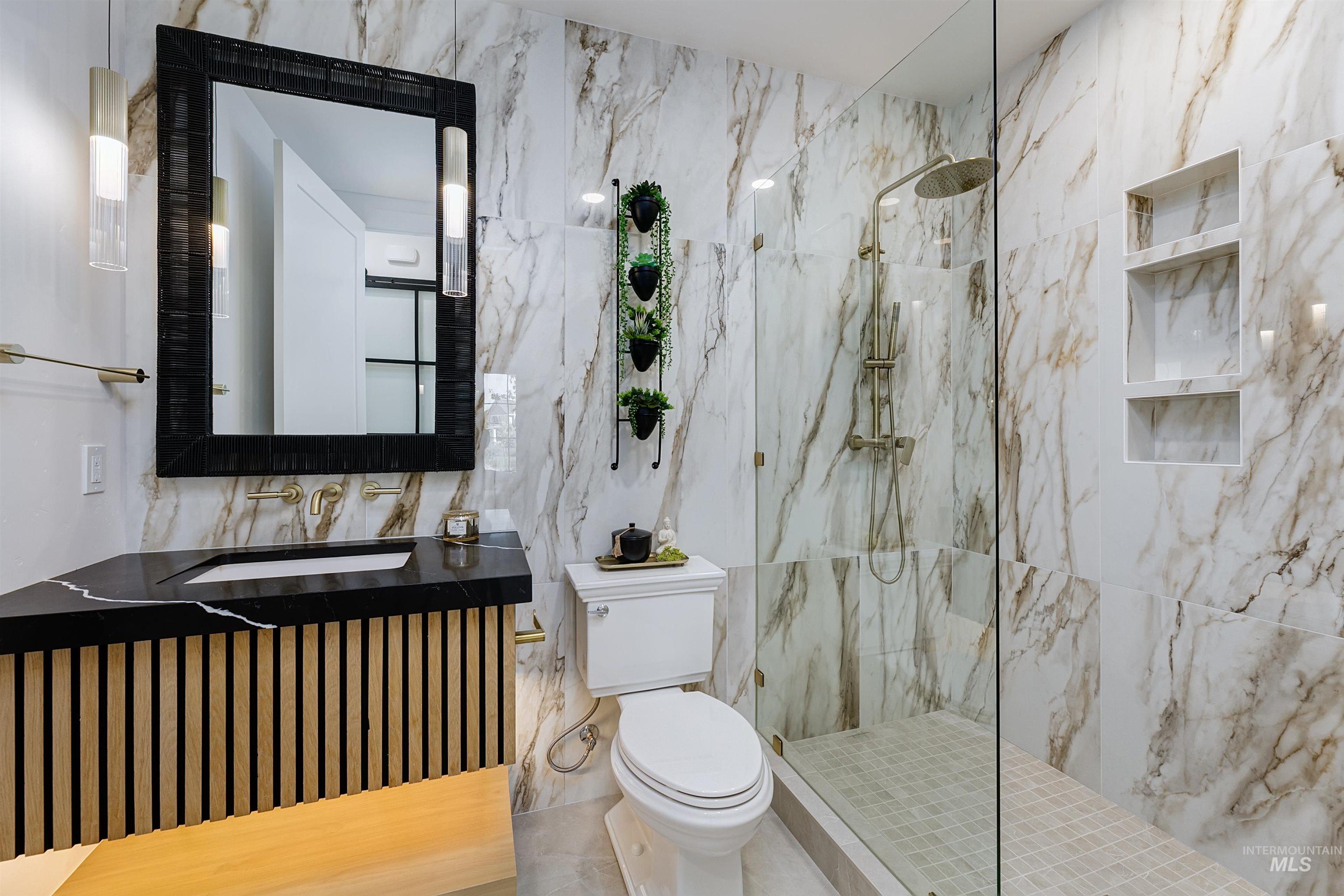Bathroom featuring a marble finish shower, vanity, and tile walls