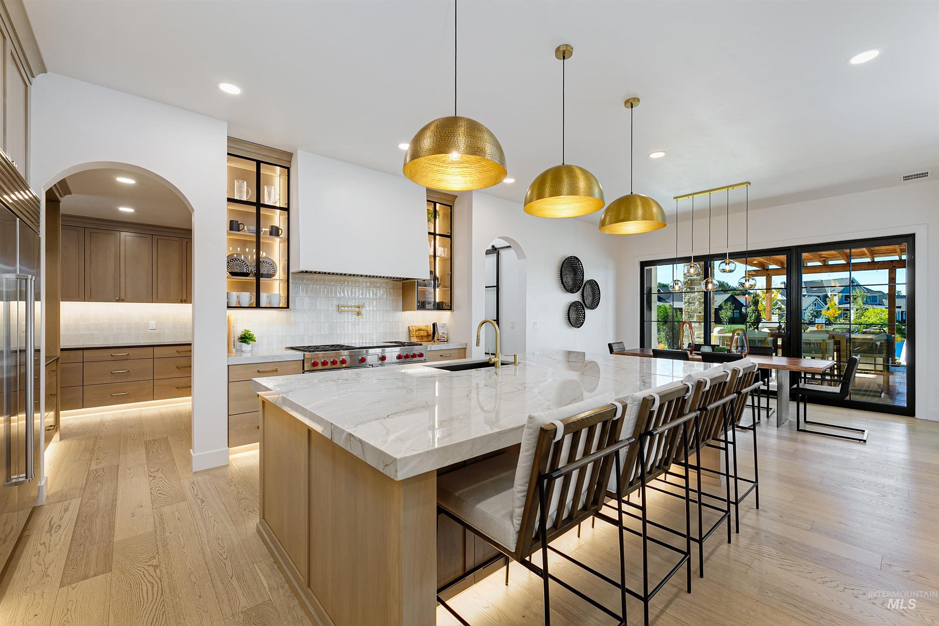 Kitchen with light stone counters, decorative light fixtures, a spacious island, a kitchen breakfast bar, and recessed lighting