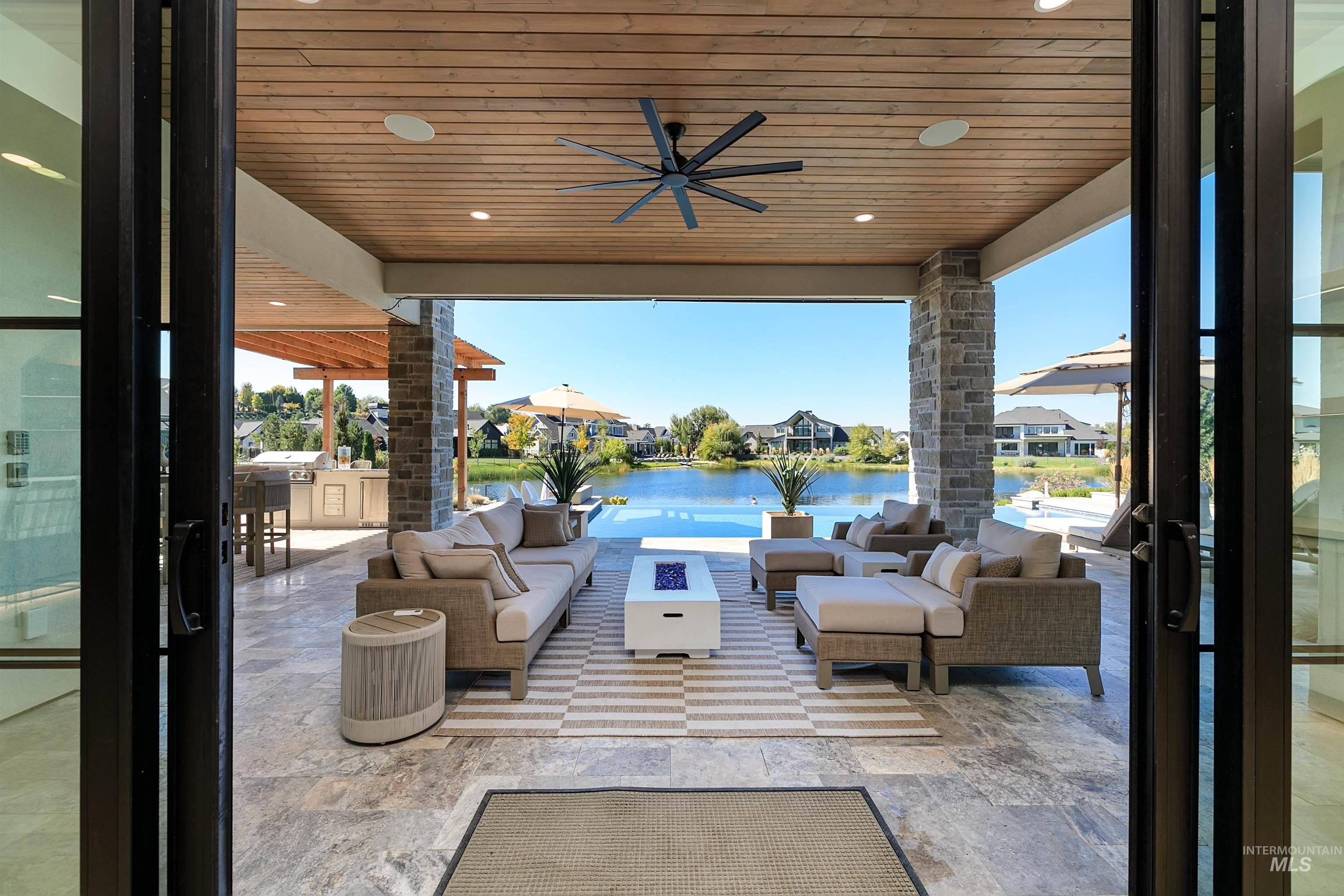 View of patio / terrace with ceiling fan, an outdoor living space, an outdoor kitchen, a water view, and a residential view