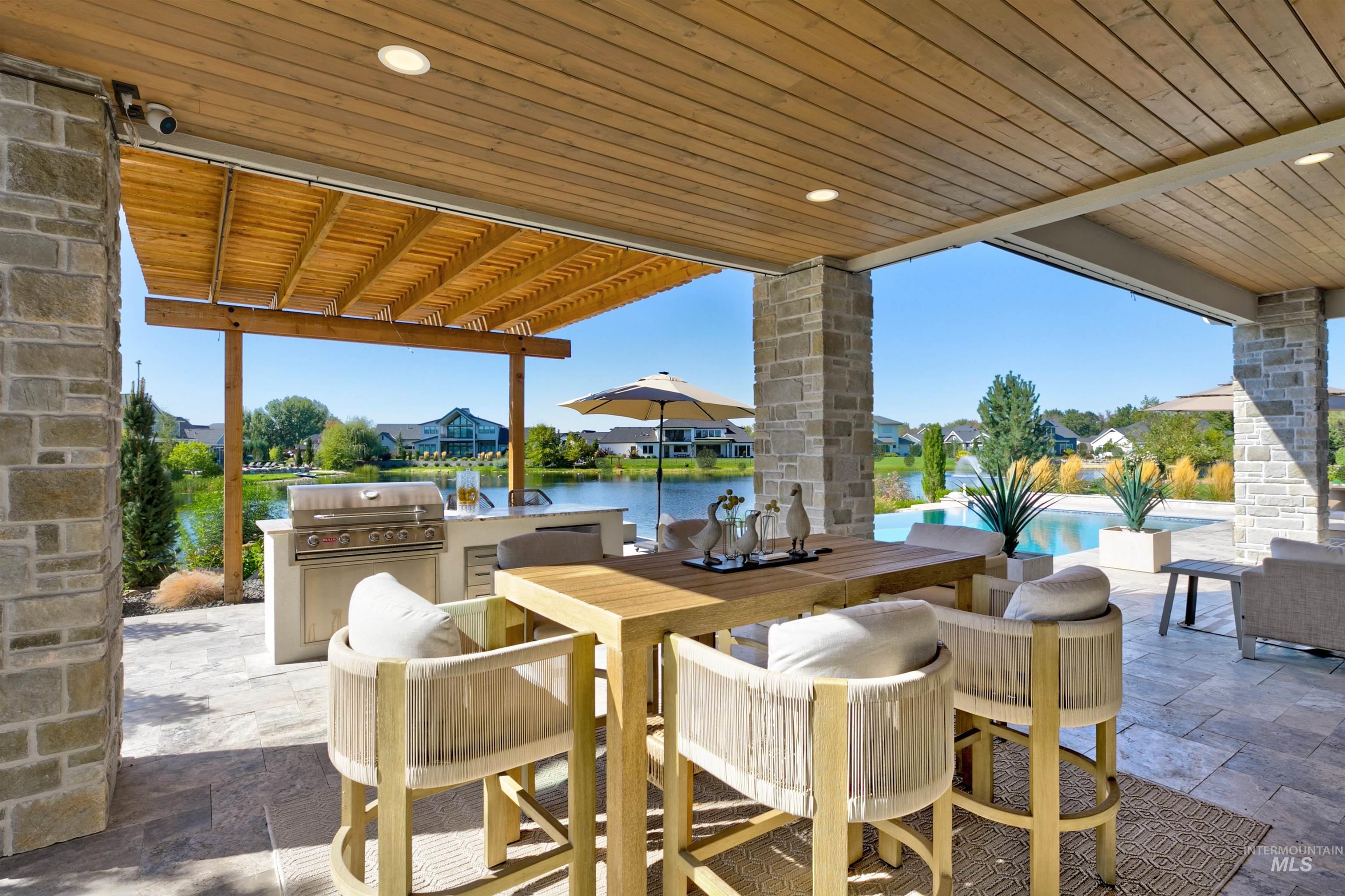 View of patio featuring an outdoor kitchen, outdoor dining space, a water view, and a pergola