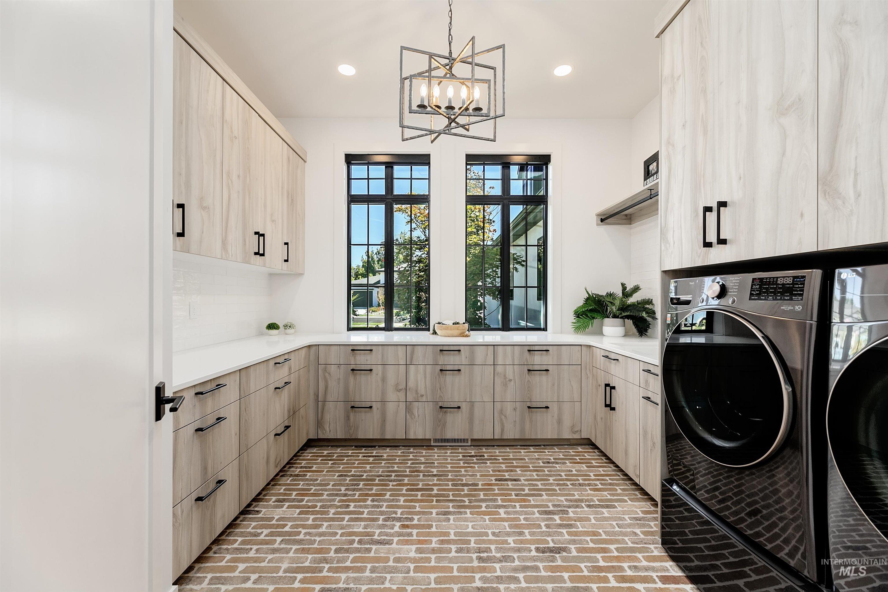 Laundry room featuring brick flooring, cabinet space, recessed lighting, a chandelier, and independent washer and dryer