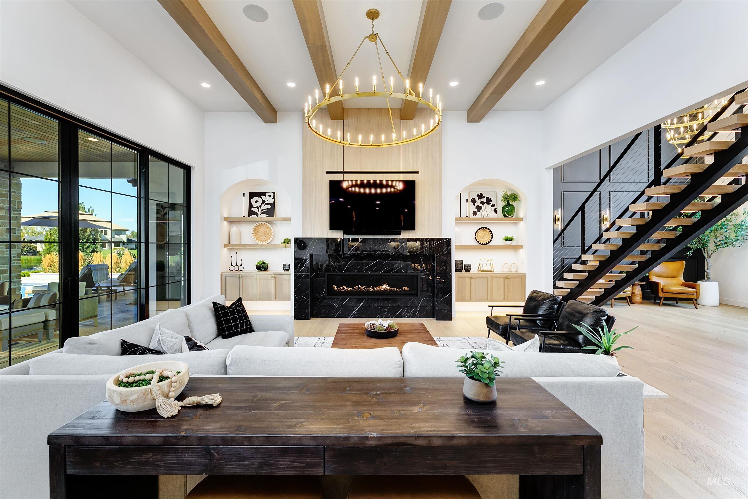 Living area featuring built in shelves, a premium fireplace, beam ceiling, wood finished floors, and stairway