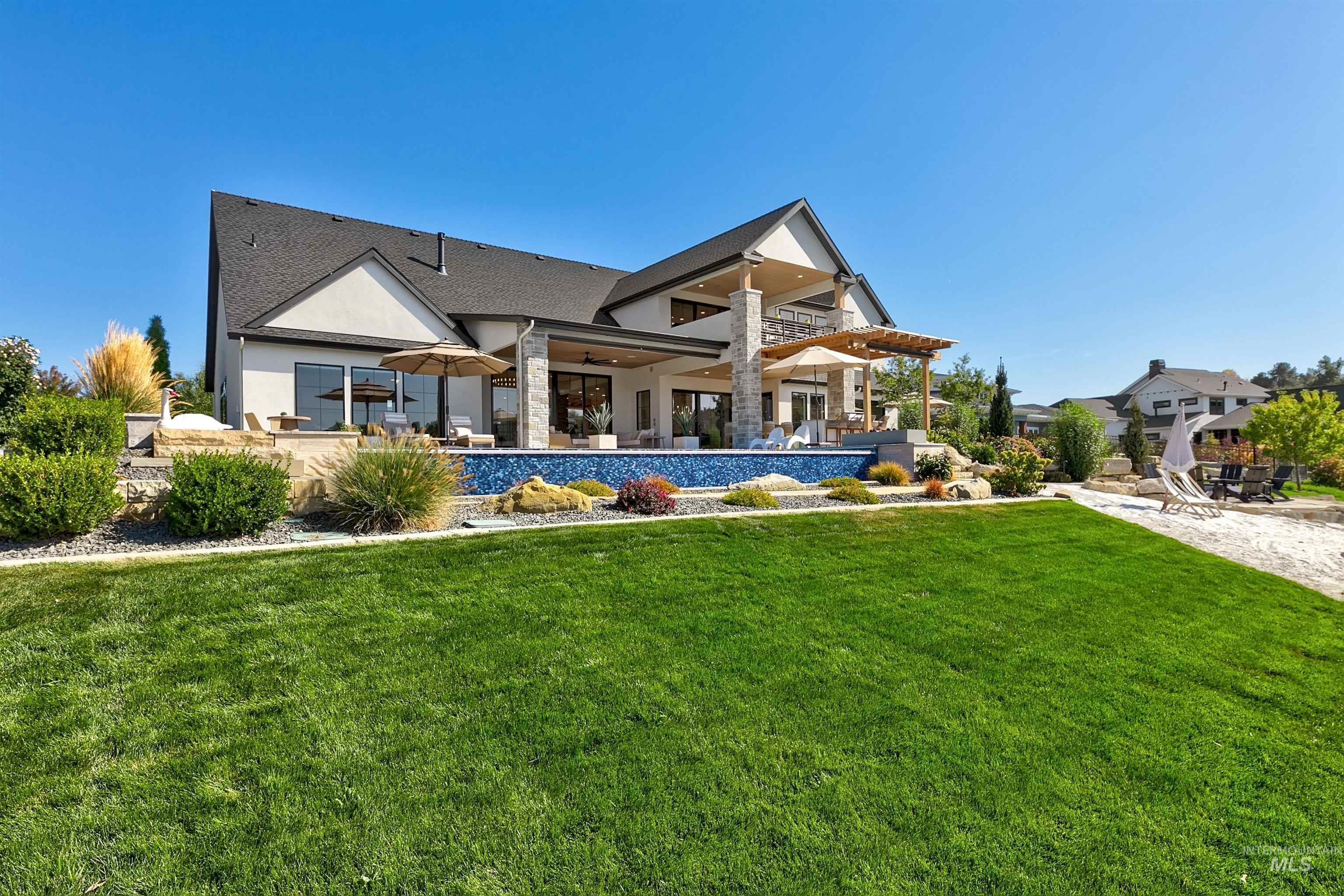 Back of house with a patio, a yard, ceiling fan, a balcony, and stucco siding