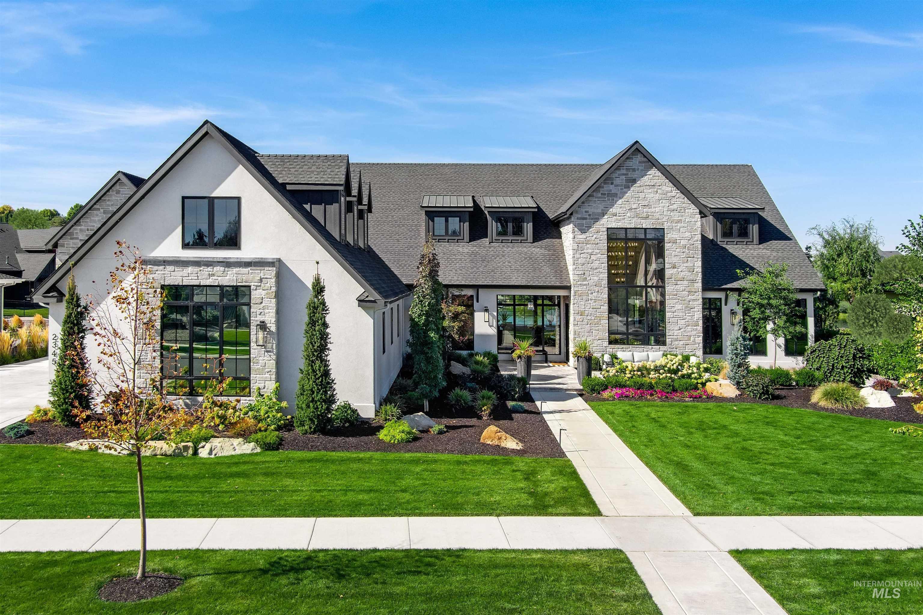 View of front of house with stone siding, a front lawn, and a shingled roof