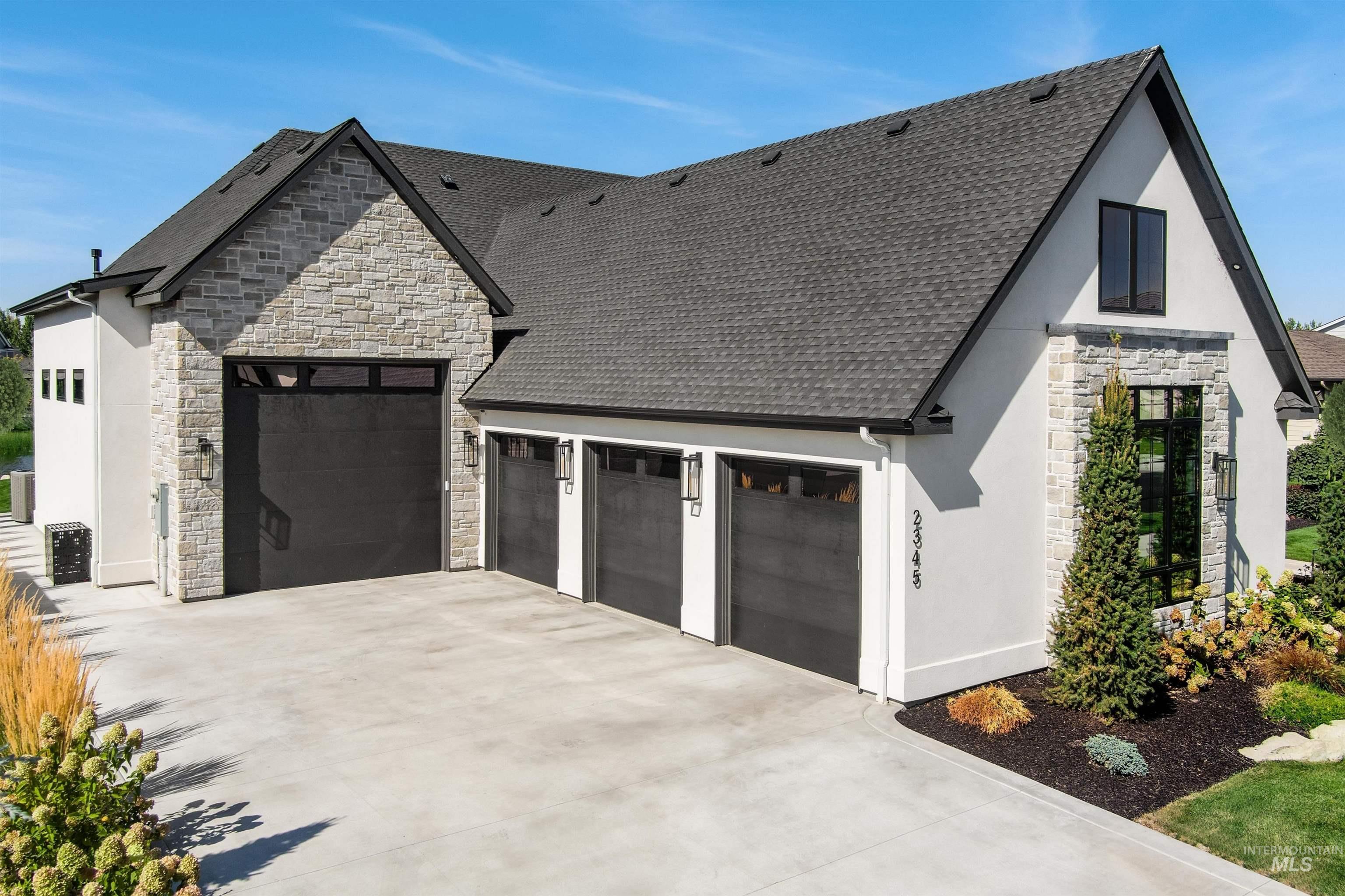 View of front of home featuring stone siding, driveway, stucco siding, an attached garage, and roof with shingles