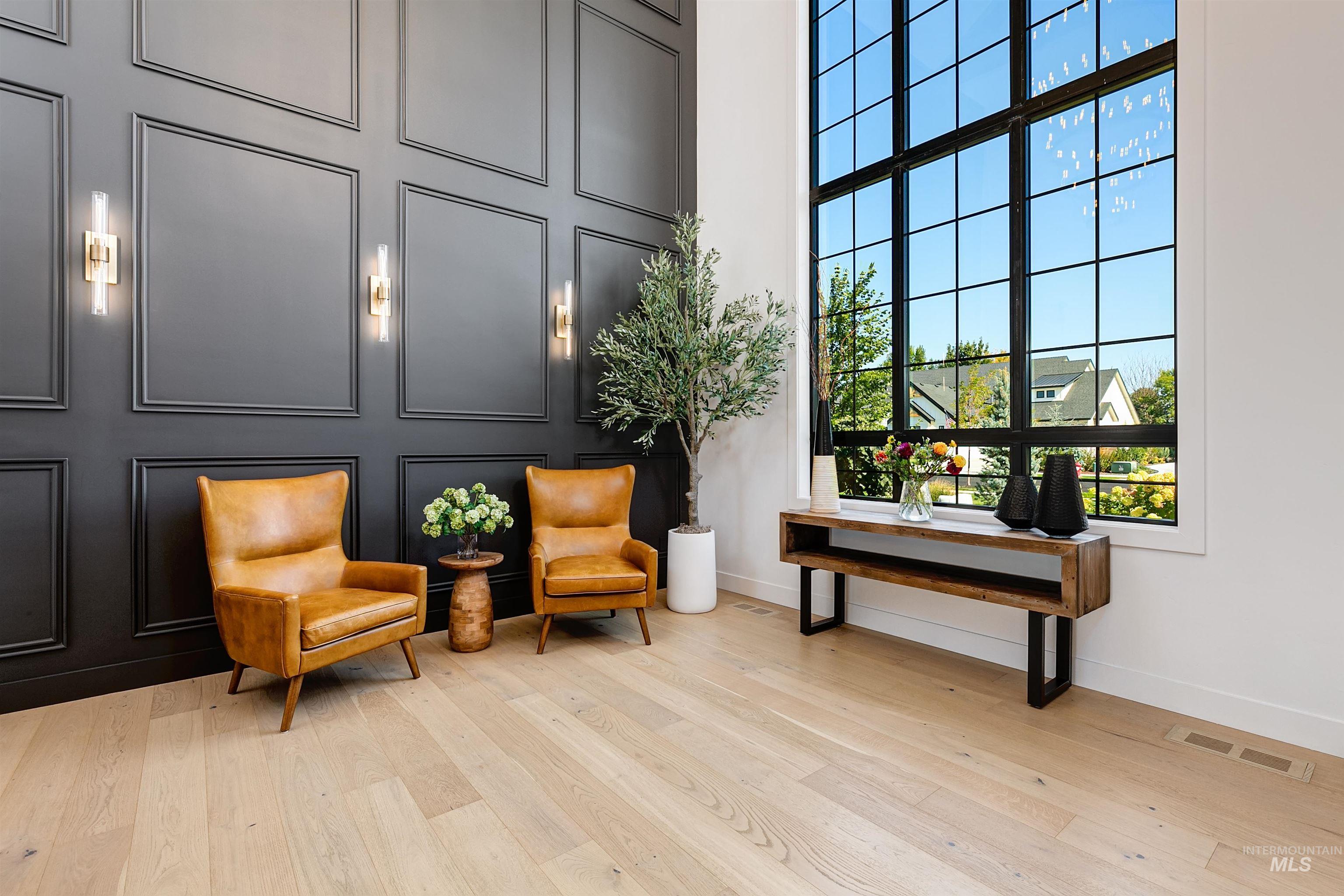 Sitting room featuring a decorative wall, light wood finished floors, and a high ceiling