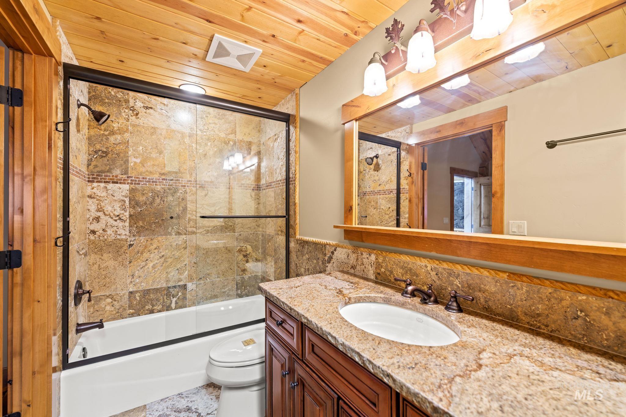 Full bathroom with wood ceiling, enclosed tub / shower combo, and vanity