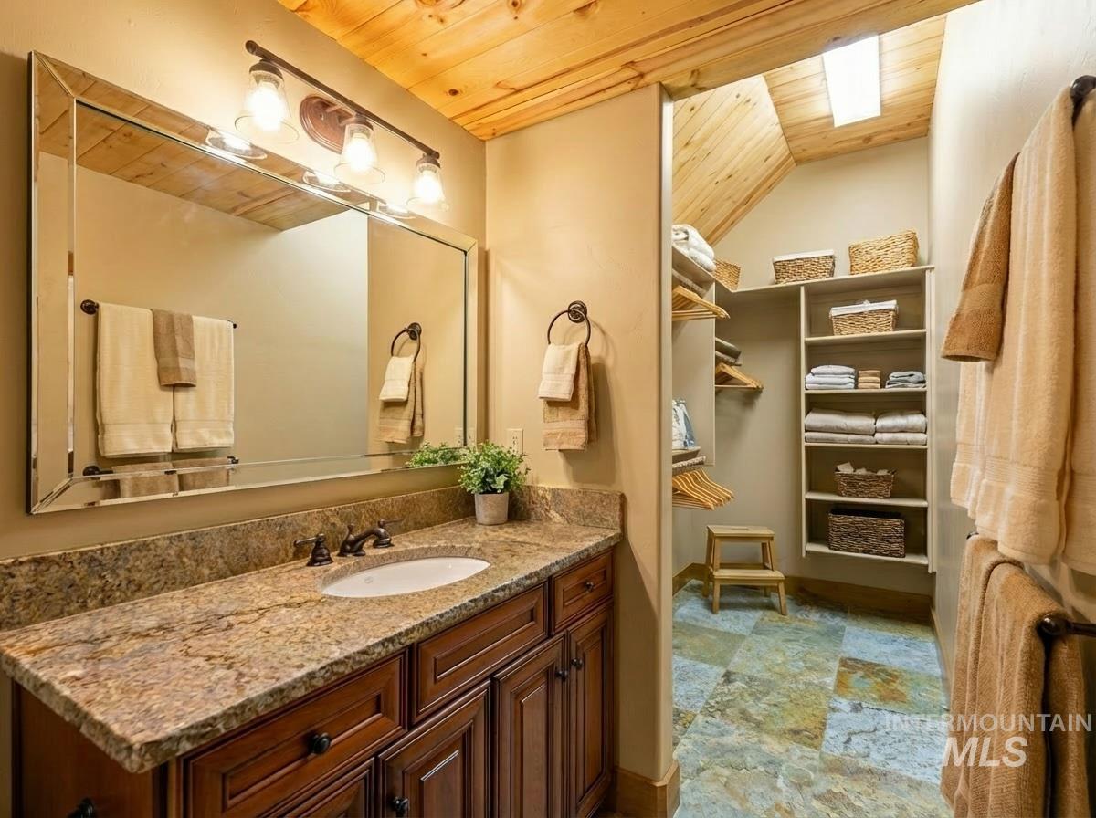 Bathroom with wooden ceiling, lofted ceiling, vanity, a skylight, and a spacious closet