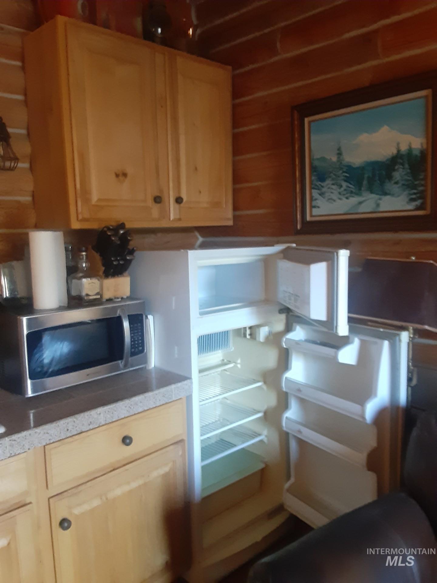 Kitchen view of stainless steel microwave, light countertops, and wooden walls