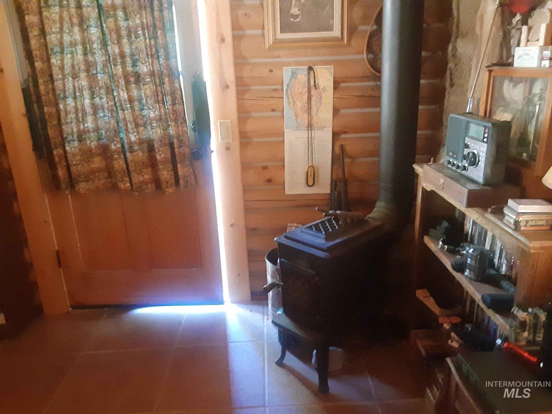 Sitting room with a wood stove, log walls, and tile patterned flooring