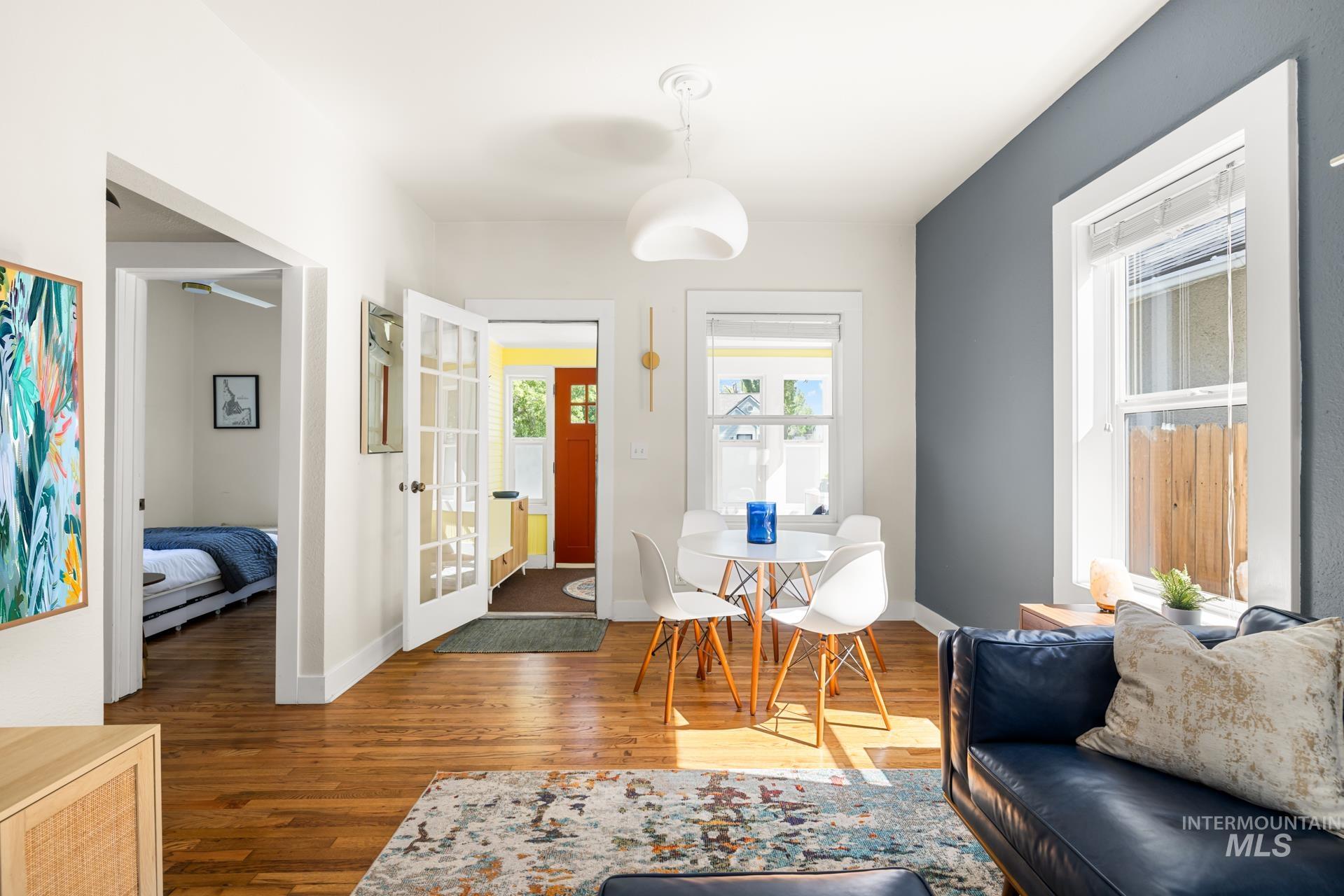 Hardwood flooring throughout the living area, featuring a contrasting accent wall and multiple windows