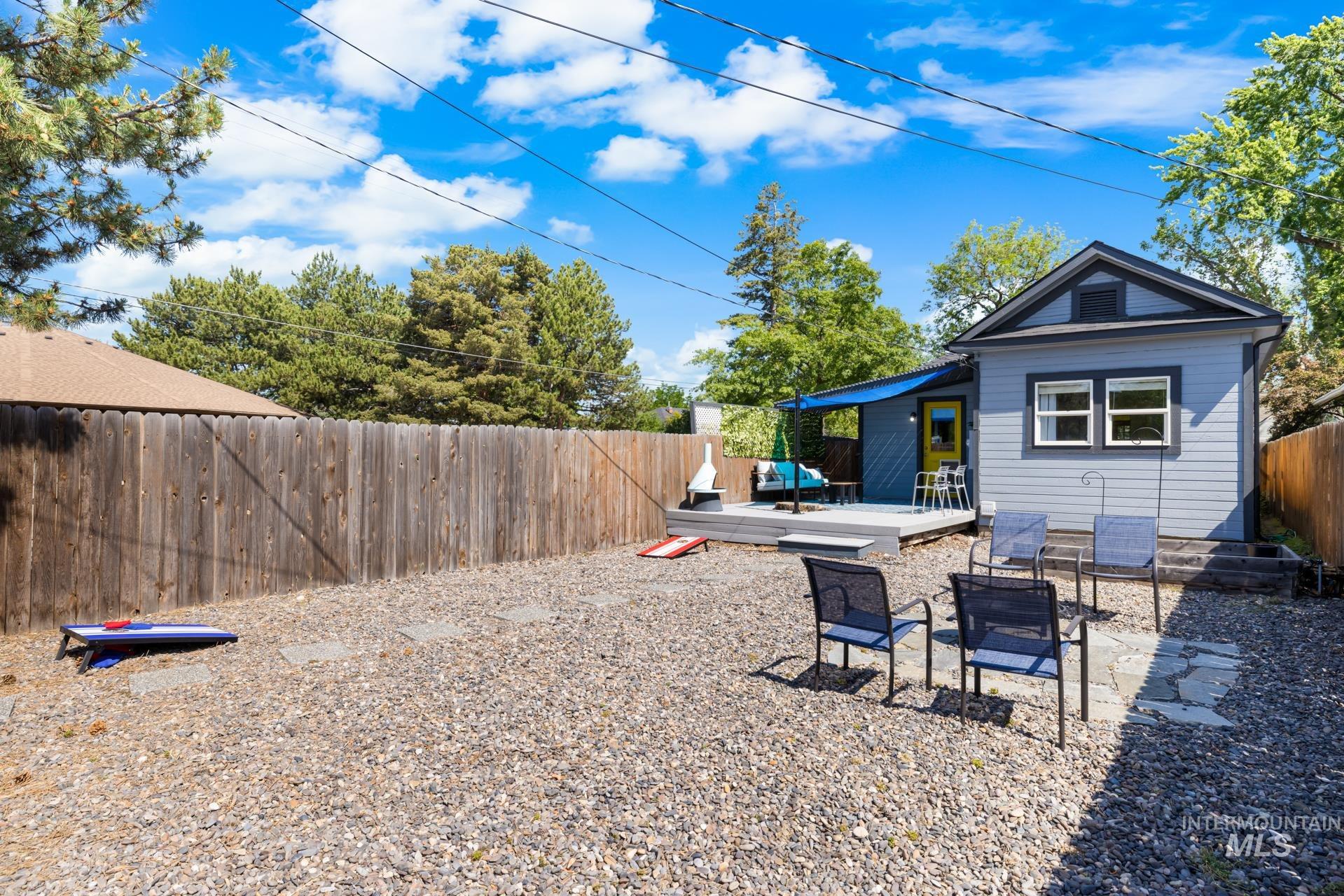 Spacious backyard featuring a large gravel area, wood privacy fencing, and a raised wood deck