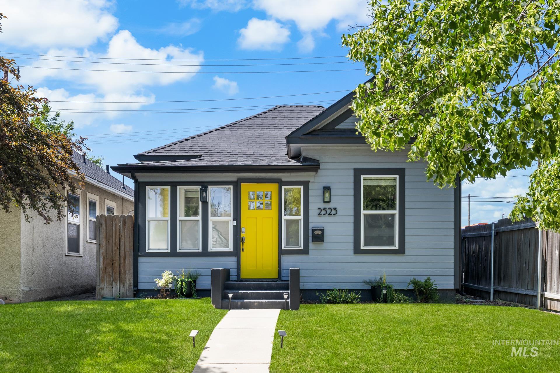 Light blue siding exterior featuring a contrasting dark trim and a vibrant yellow entry door with multiple glass panes
