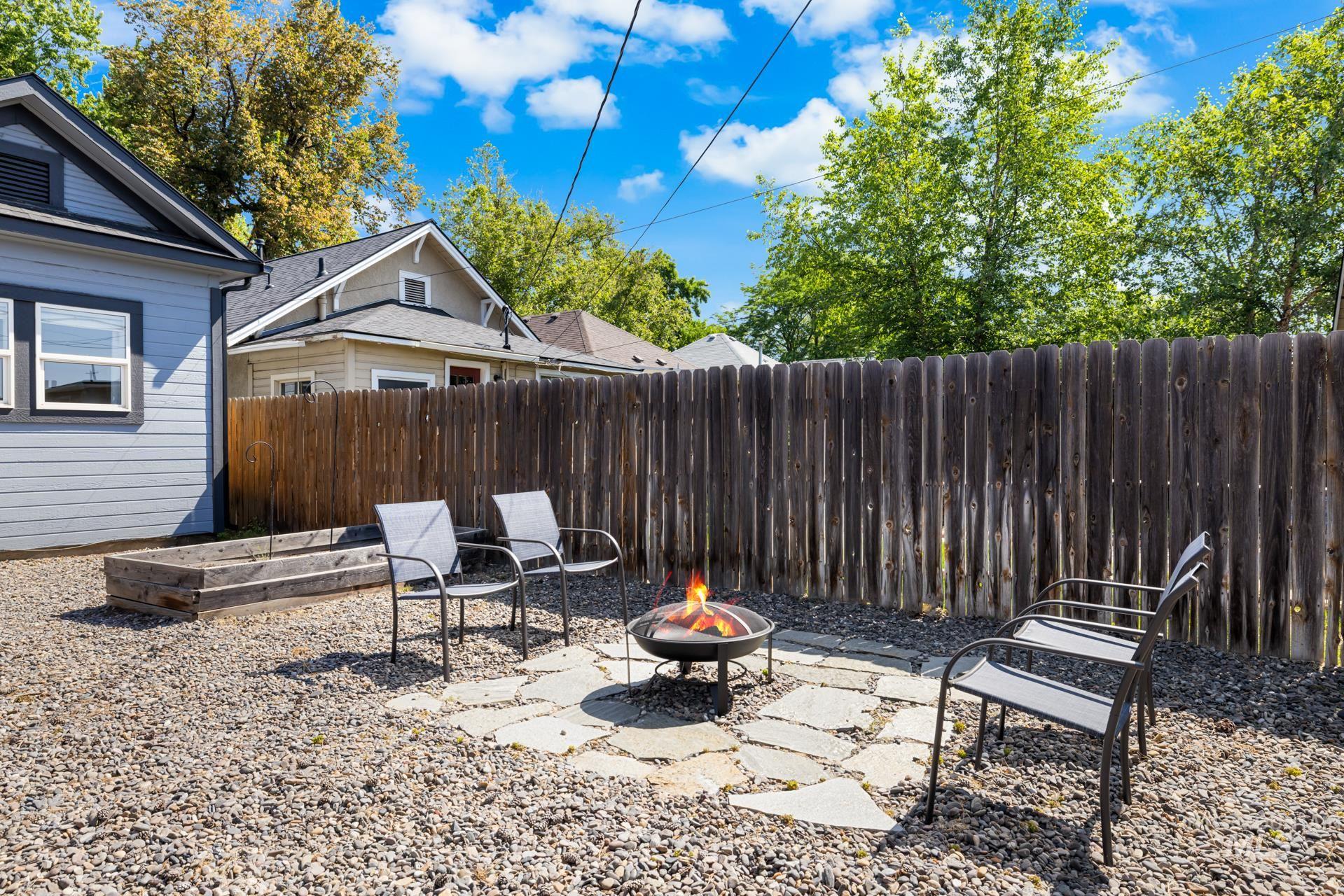 Gravel backyard featuring a natural stone patio with a central fire pit