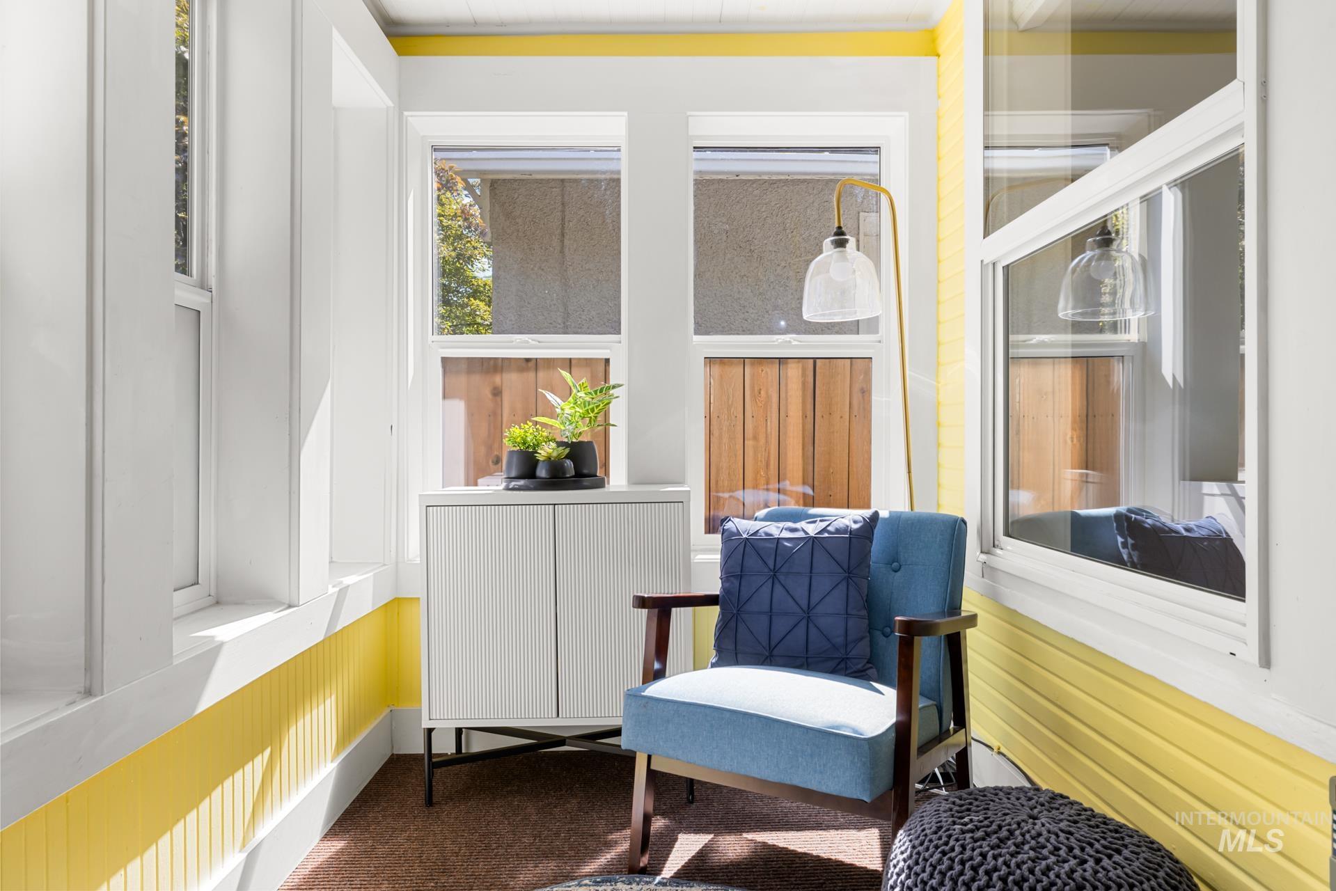 Sunroom featuring multiple windows, a white paneled storage cabinet, and white trim with a yellow accent