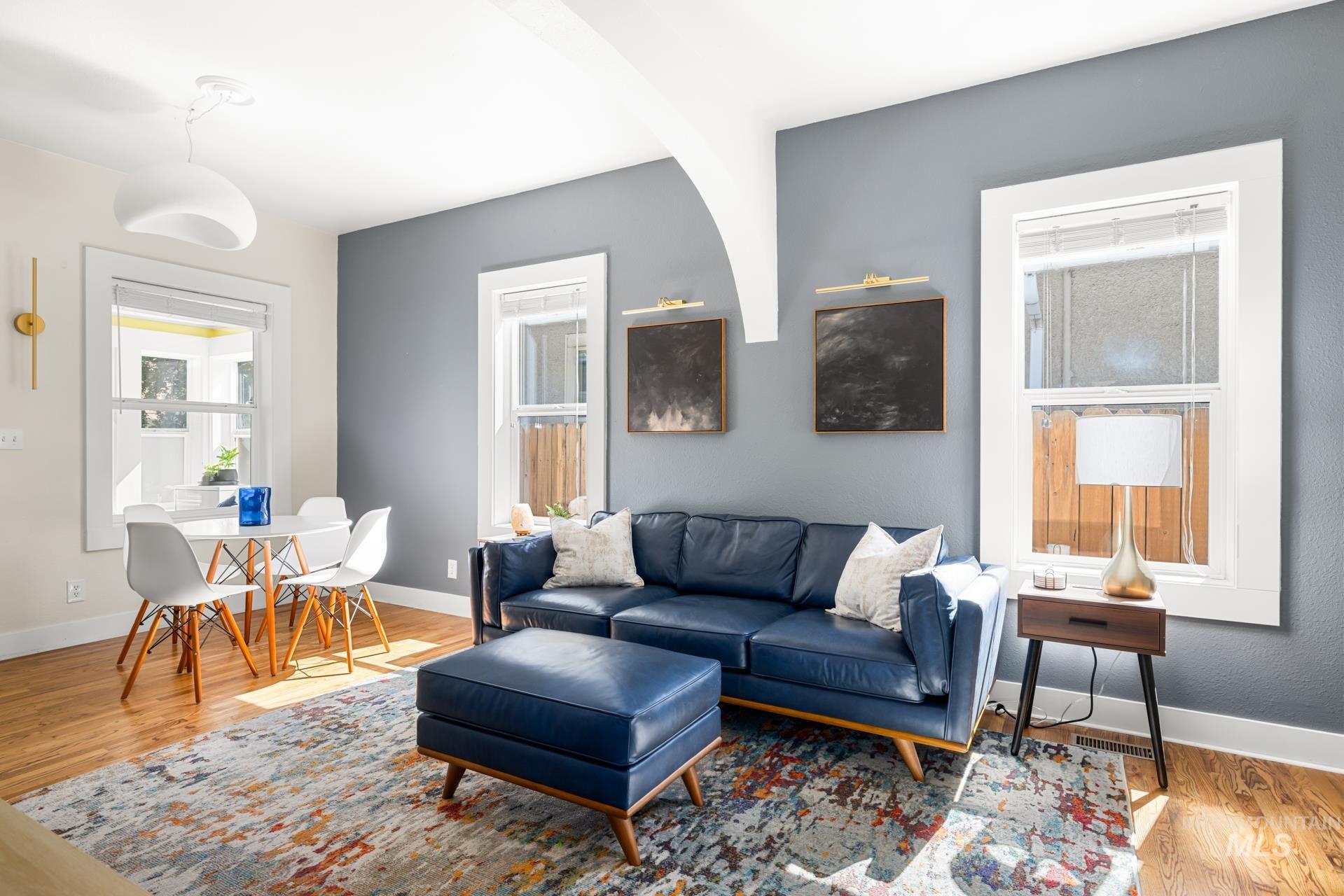 Open-concept living area with wood-finish flooring, white trim, and a decorative arched wall feature
