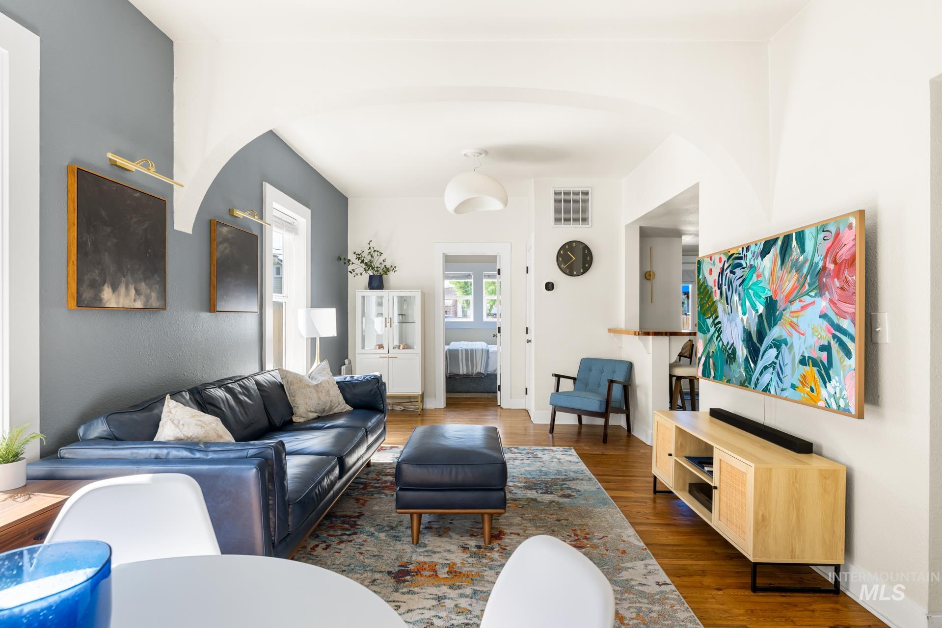 Living area featuring wood-finish flooring, a light gray accent wall, and arched doorways