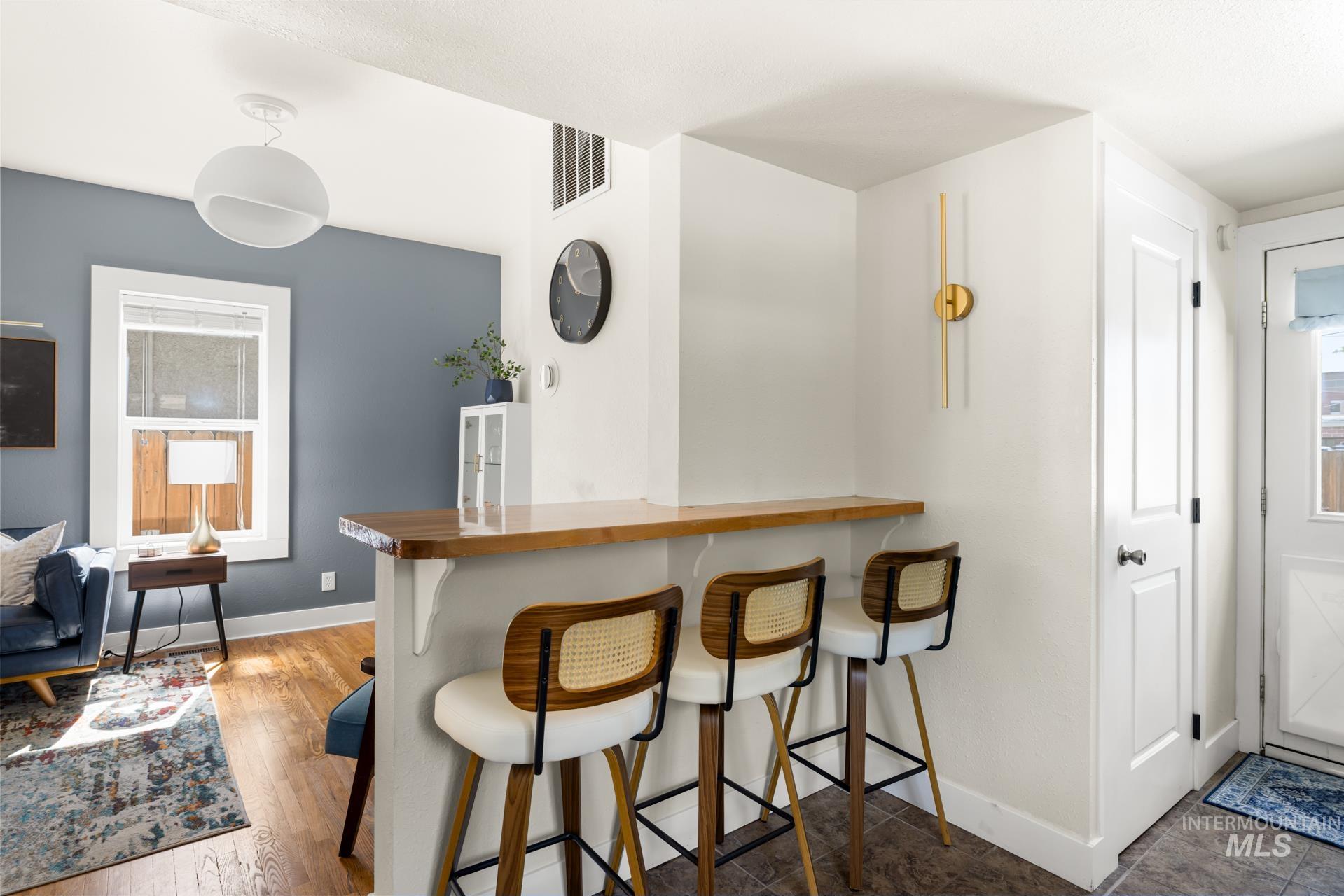 Breakfast bar with a polished wood countertop, white base, and three built-in pendant lights