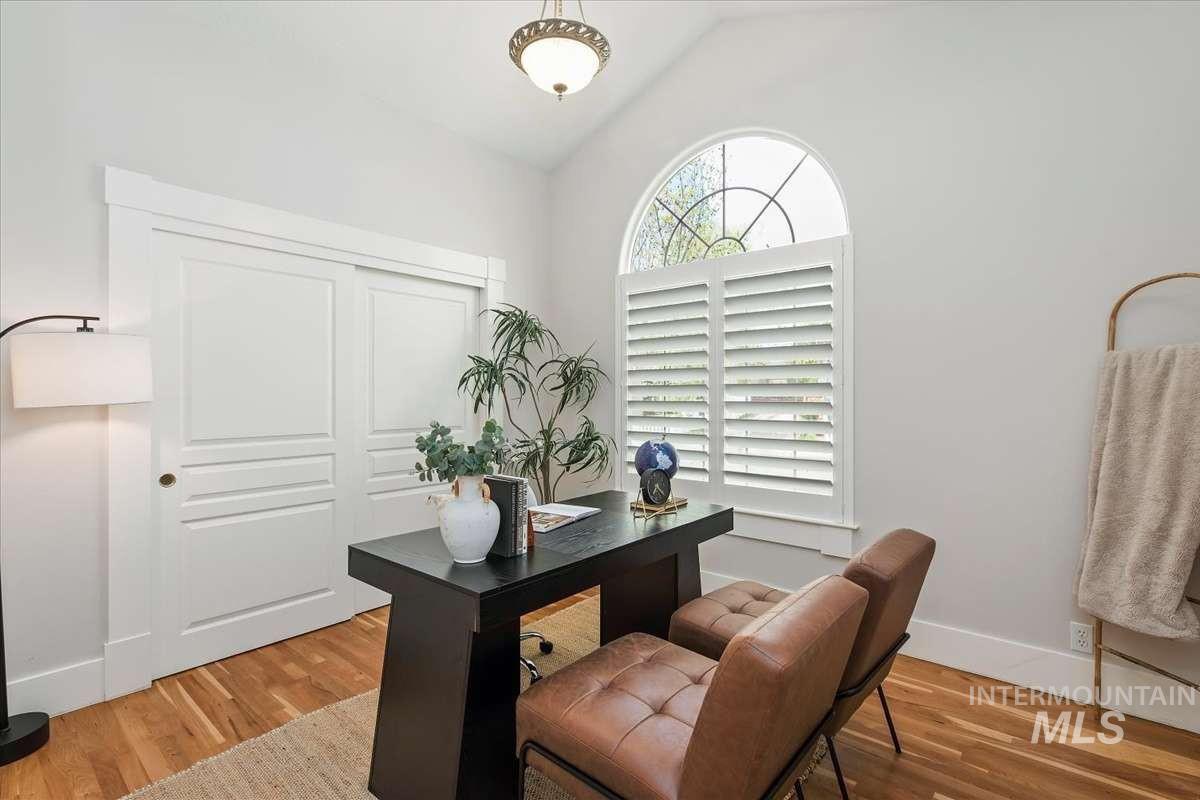 Arched window with plantation shutters, vaulted ceiling, wood-finish flooring, and a built-in closet with sliding doors