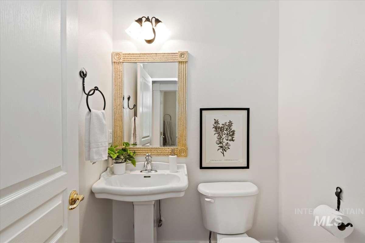 Pedestal sink with brass-finish faucet, framed mirror with decorative border, and wall-mounted light fixture