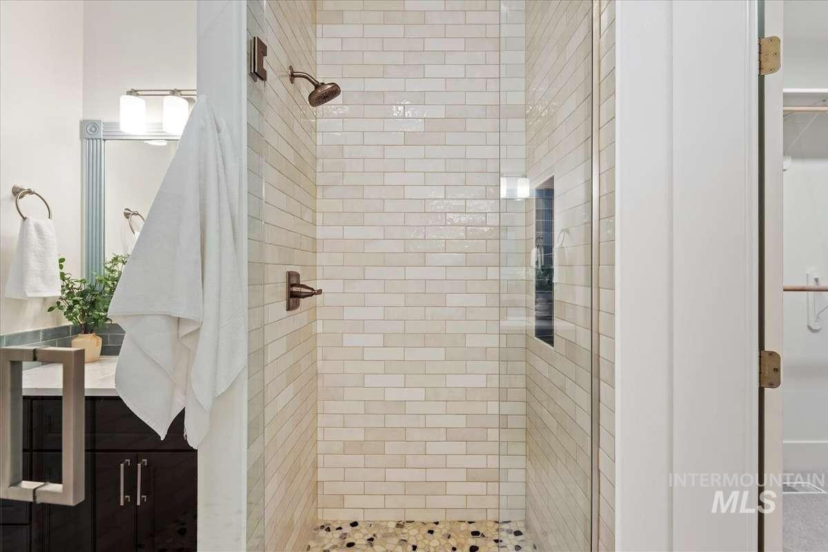 Walk-in shower featuring subway tile, a built-in niche, and a pebble tile floor