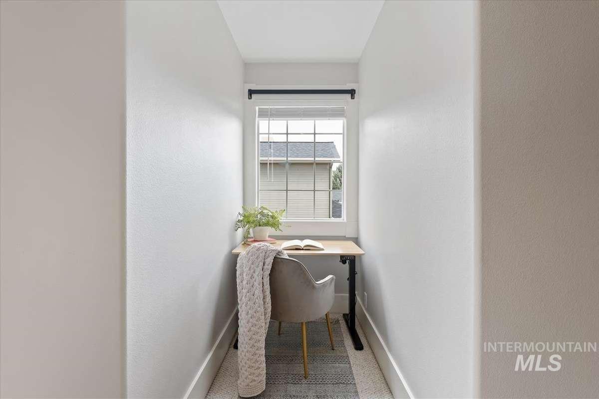 Recessed nook featuring a window with blinds, light-toned walls, and wood-finish flooring