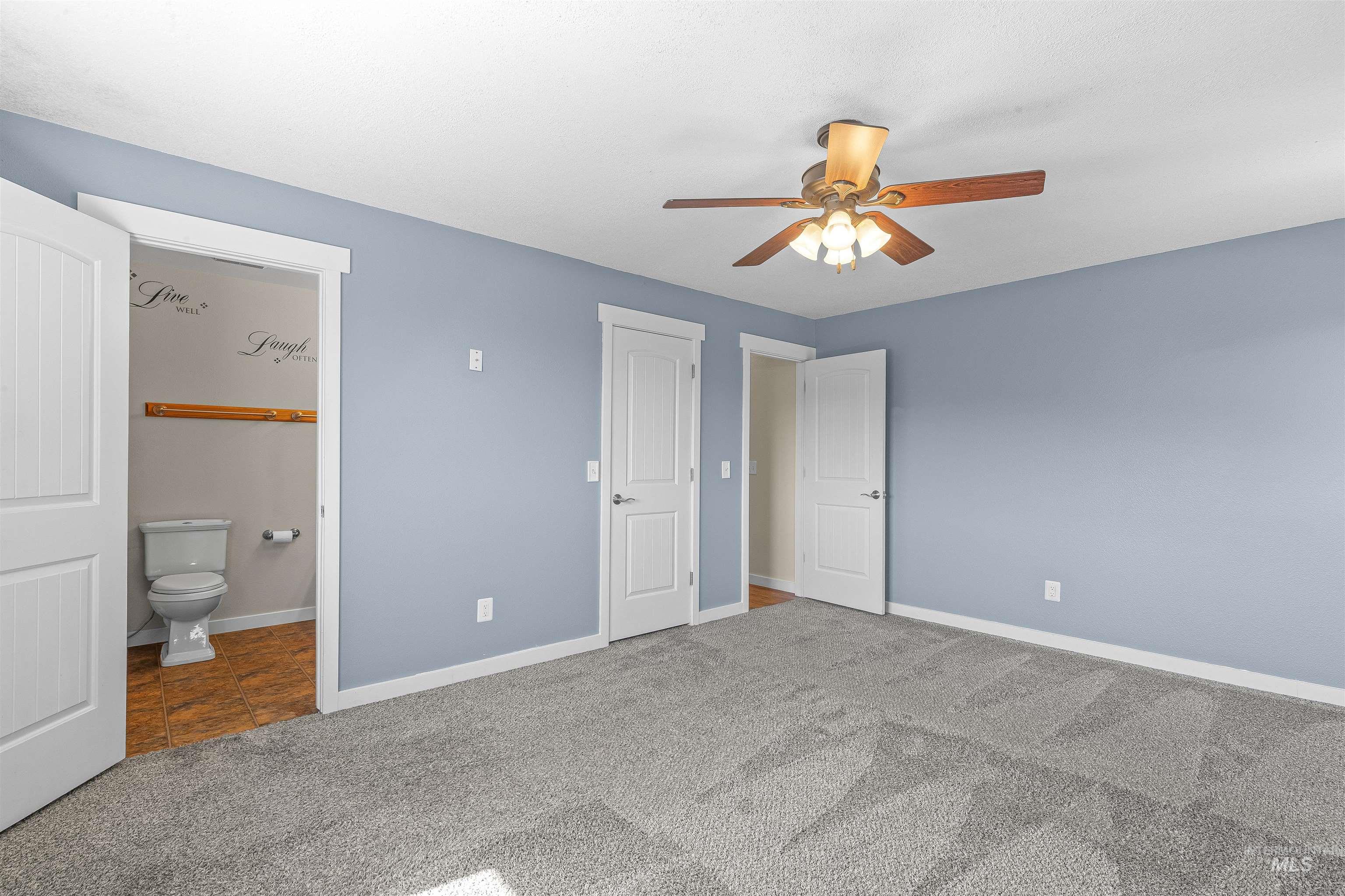 Unfurnished bedroom with carpet floors, connected bathroom, ceiling fan, and tile patterned floors