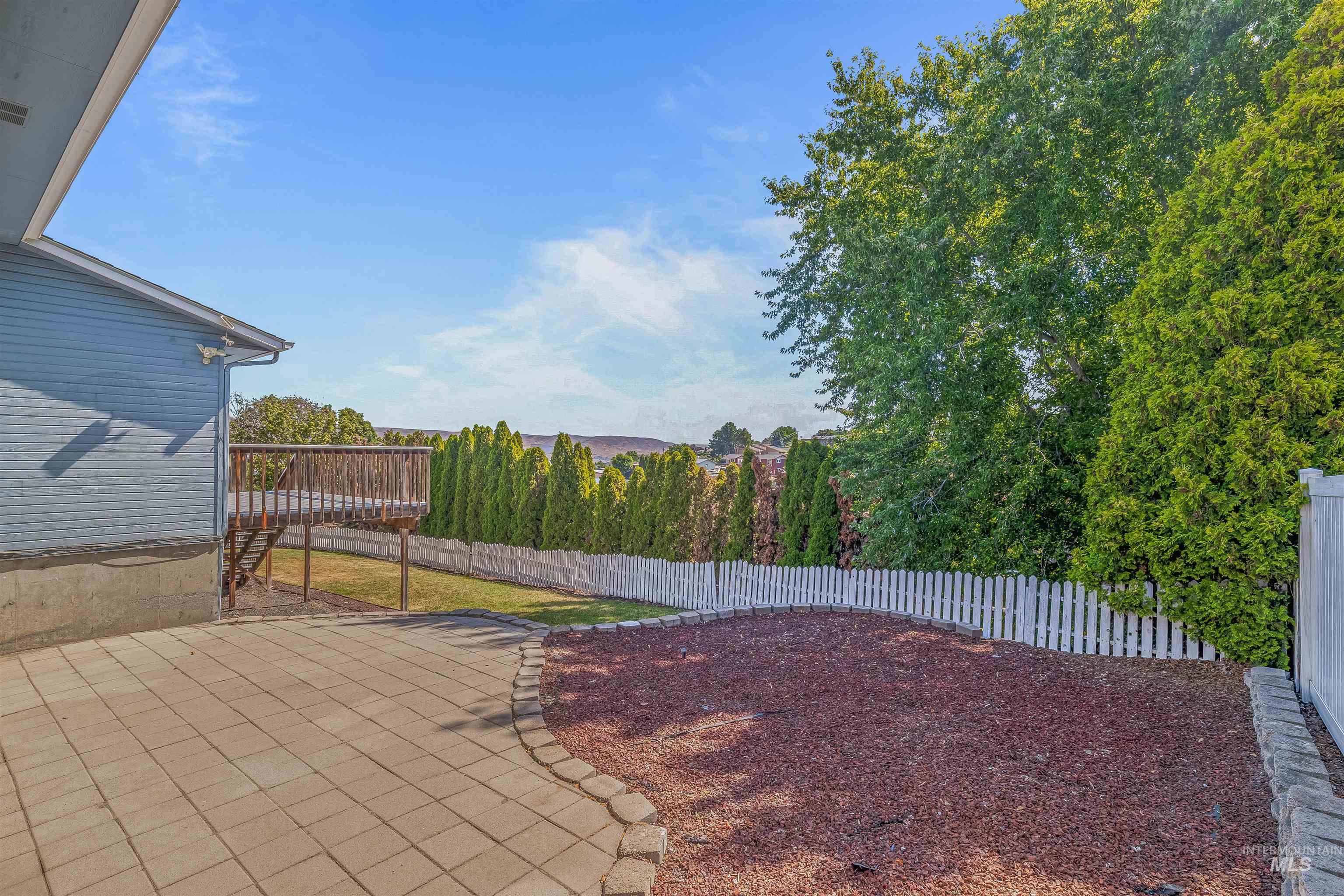 Fenced backyard featuring a patio and a wooden deck