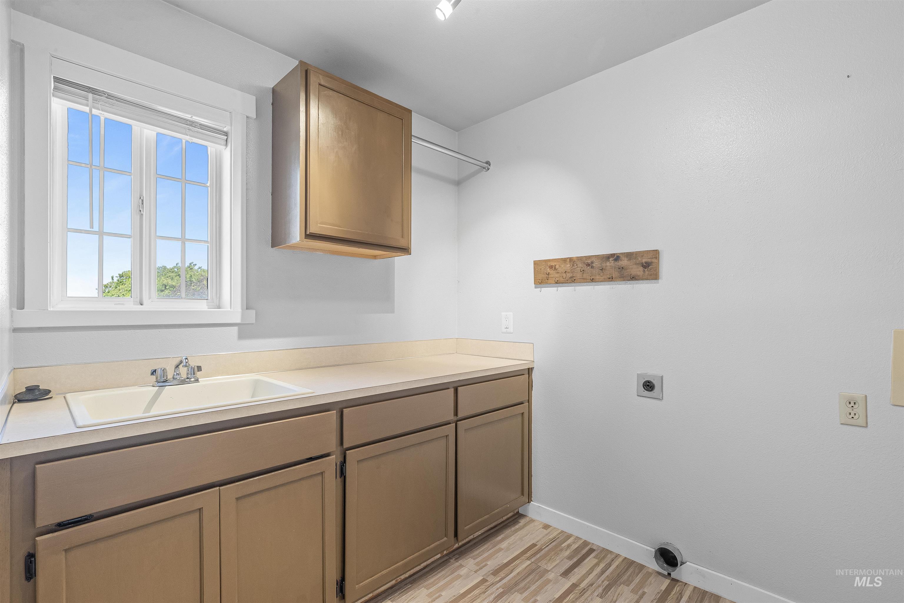 Laundry room featuring hookup for an electric dryer, light wood-style flooring, and cabinet space