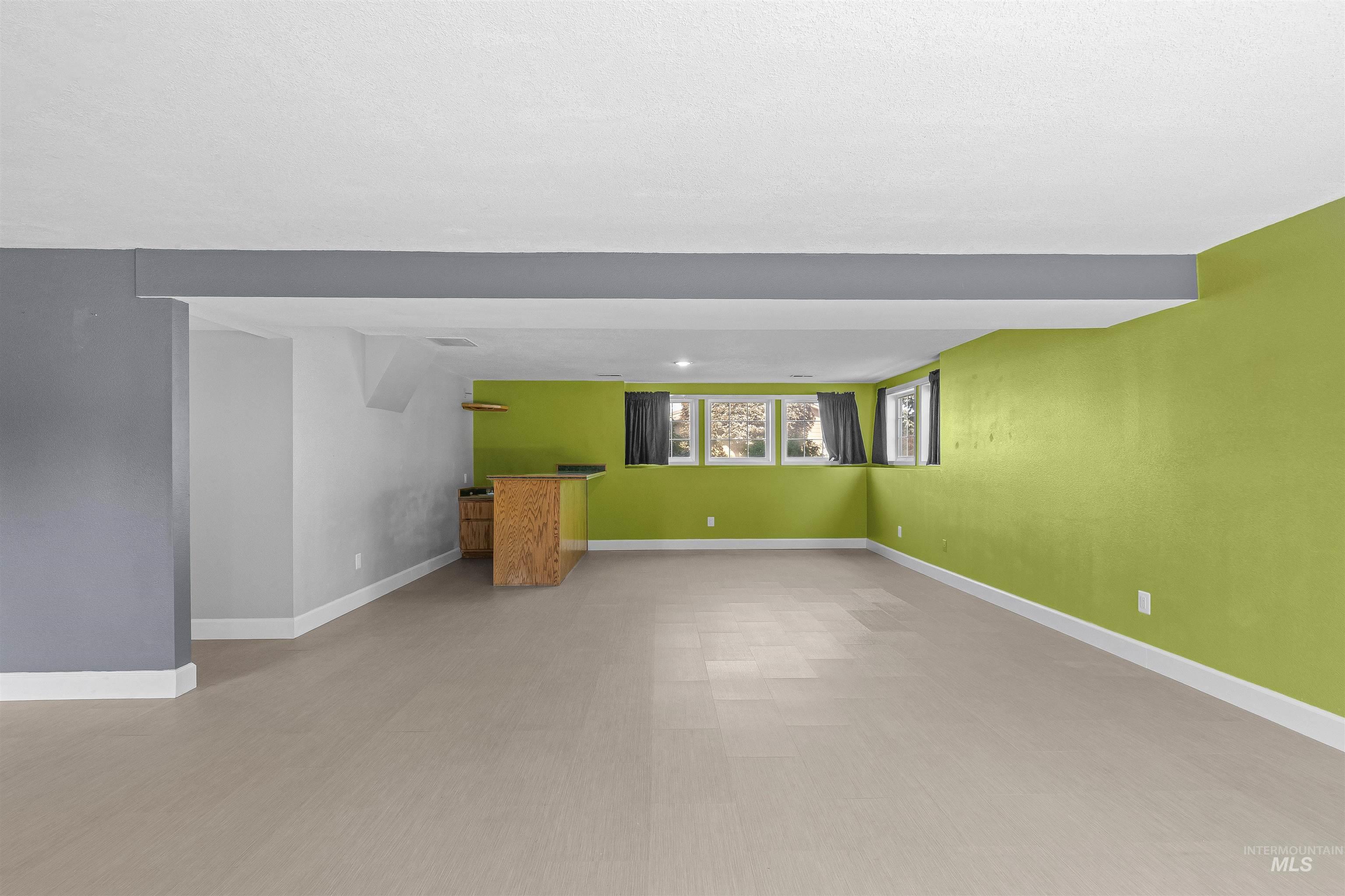 Unfurnished living room with baseboards and bar