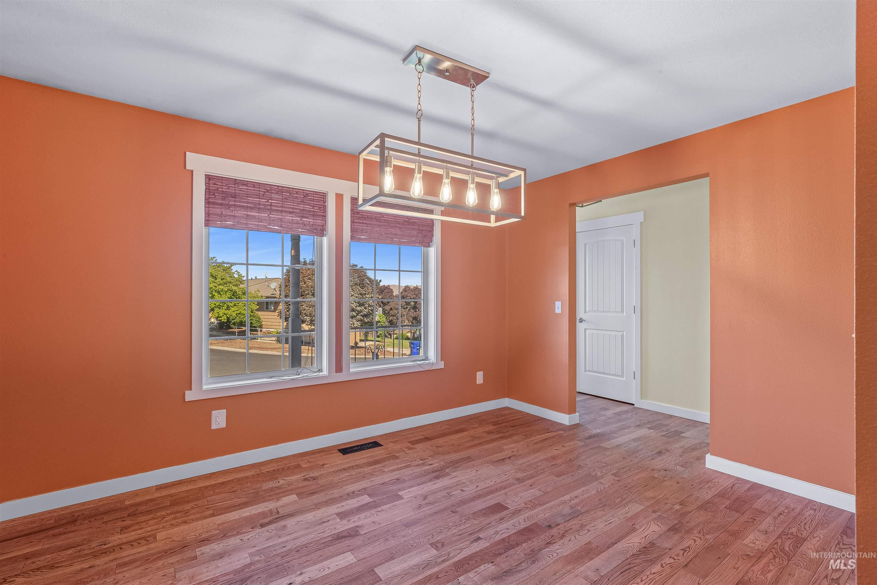 Empty room with wood finished floors and a chandelier