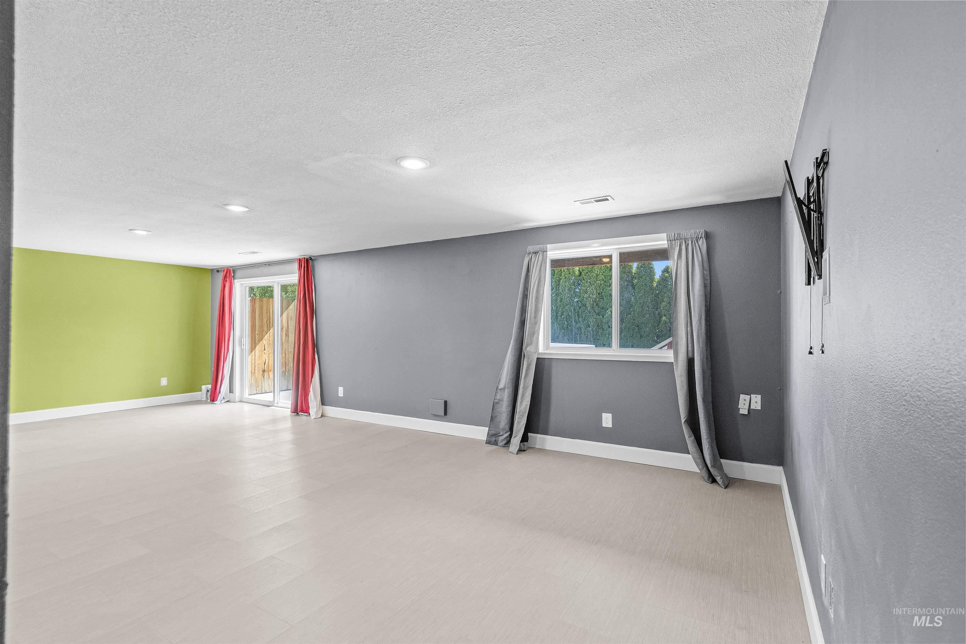 Empty room with a textured ceiling, recessed lighting, and light floors