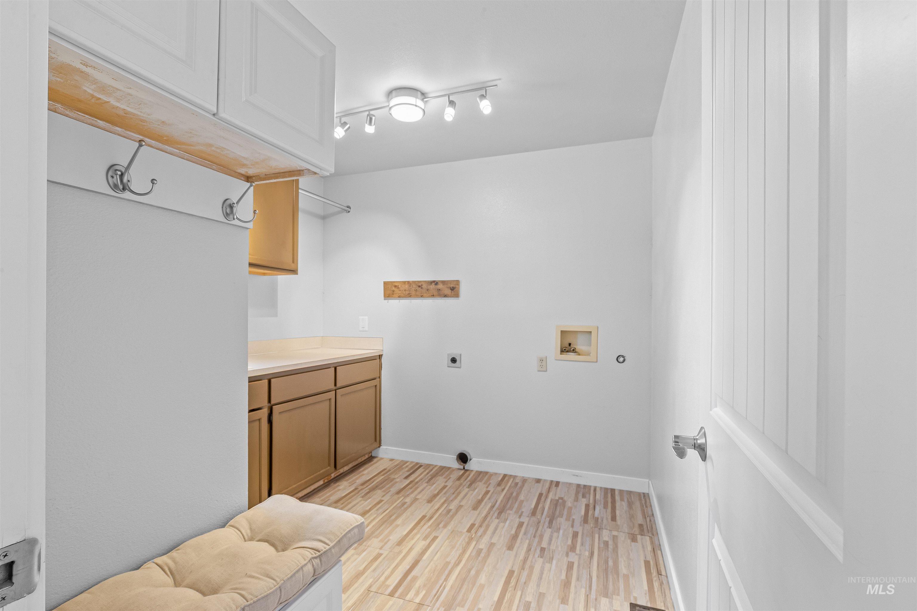 Laundry area featuring hookup for an electric dryer, cabinet space, washer hookup, and light wood-style floors