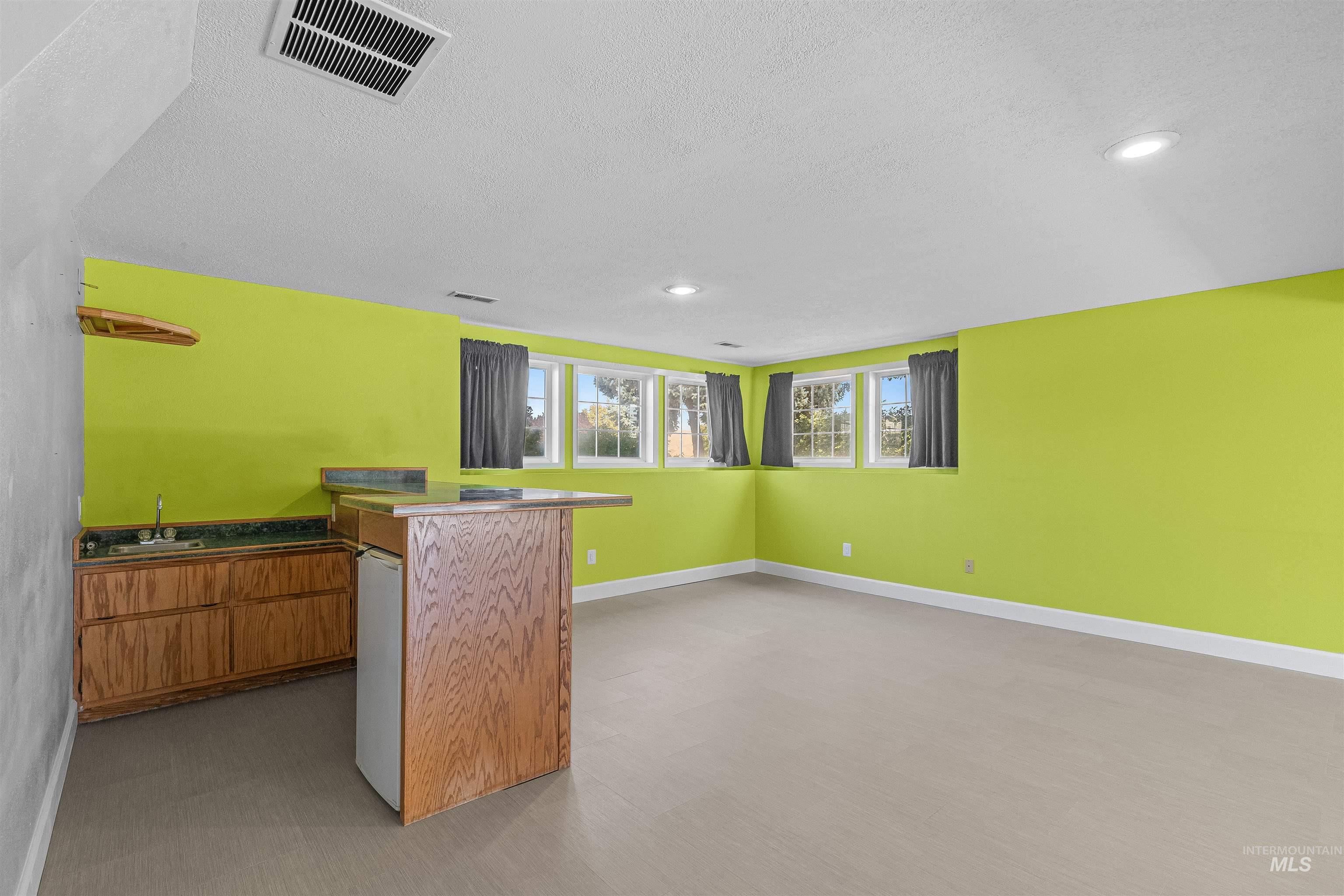 Indoor wet bar with a textured ceiling and recessed lighting