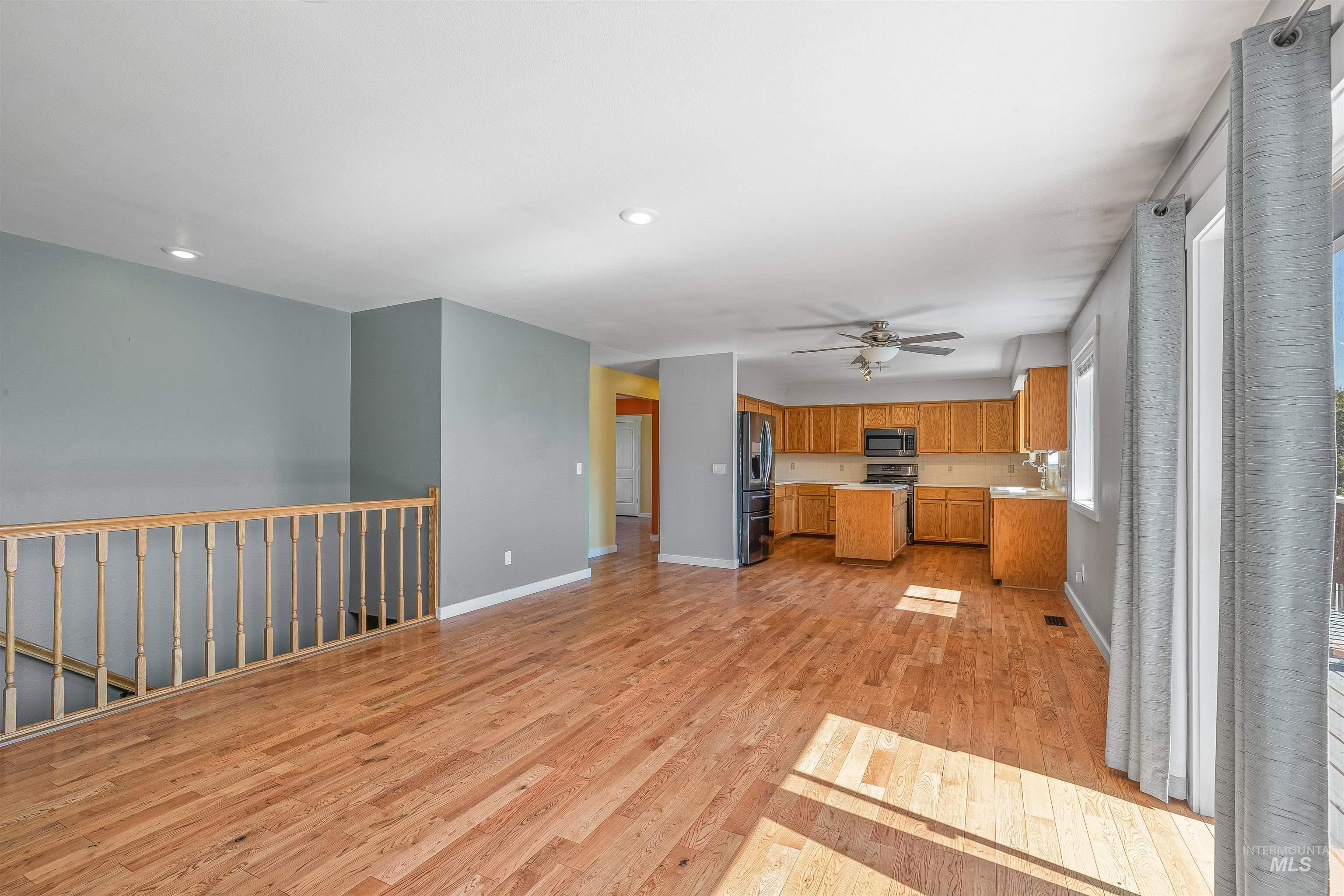 Kitchen featuring stainless steel appliances, light wood-type flooring, a ceiling fan, light countertops, and brown cabinetry