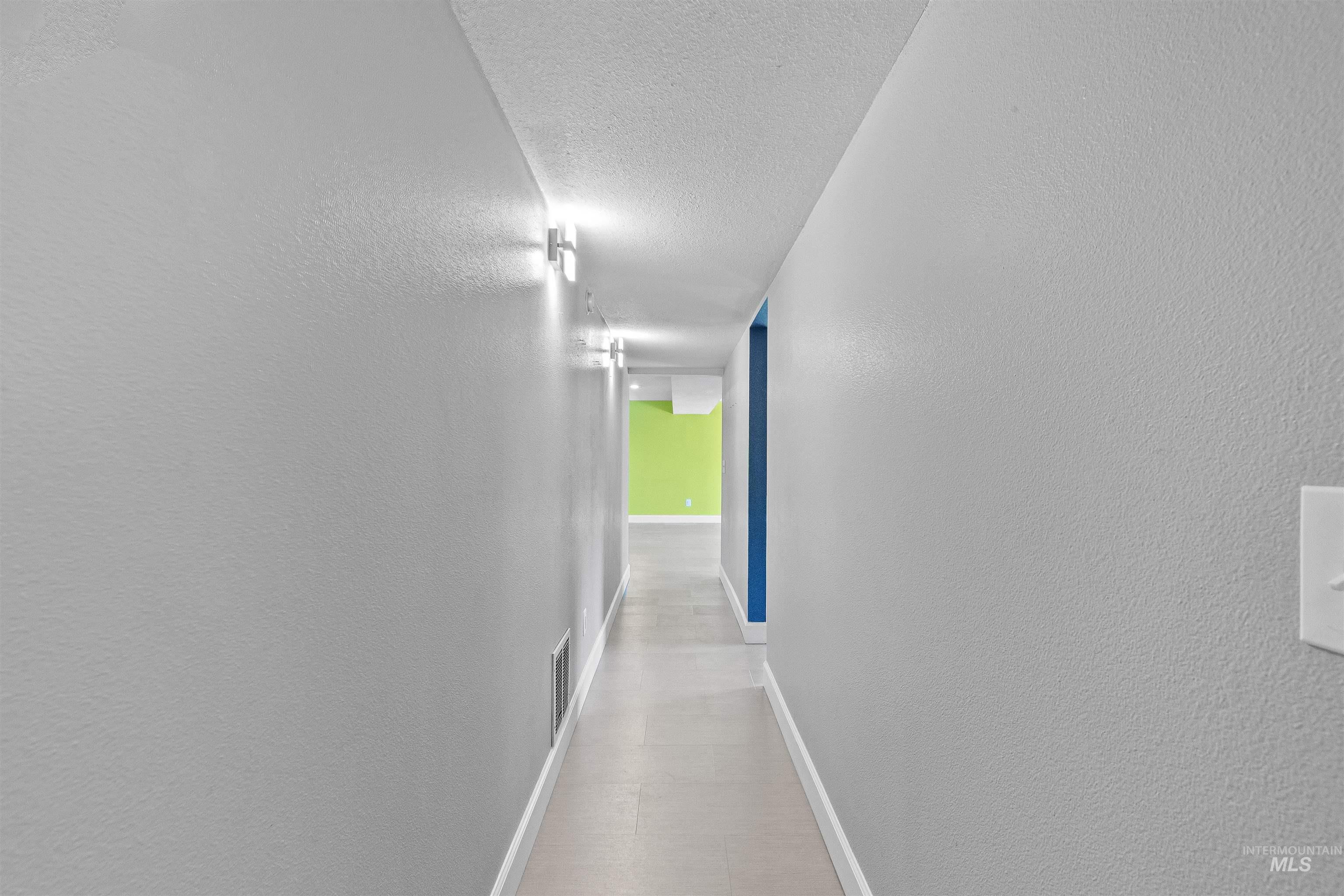 Corridor featuring a textured ceiling and baseboards