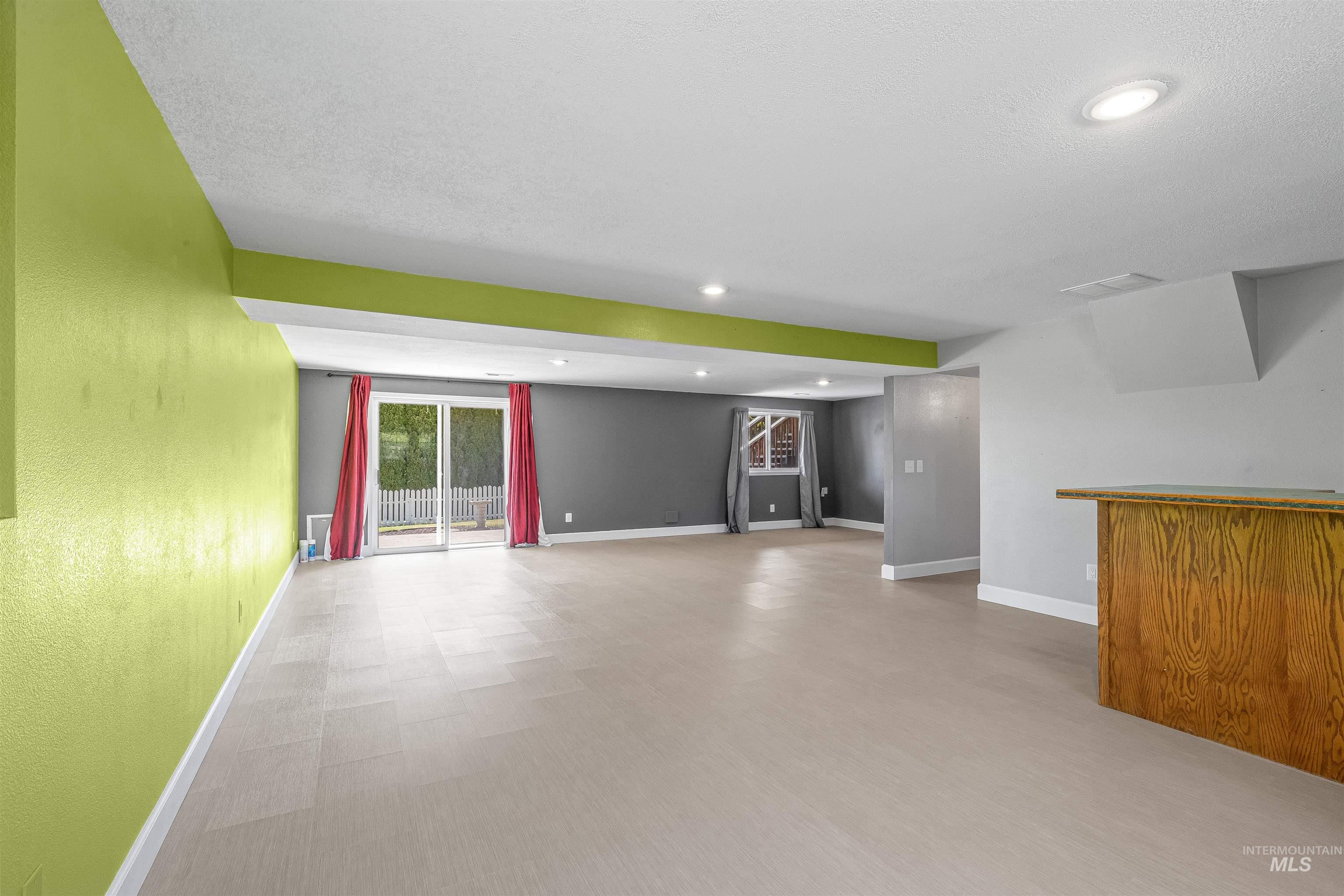 Unfurnished living room featuring a bar, wood finished floors, and recessed lighting